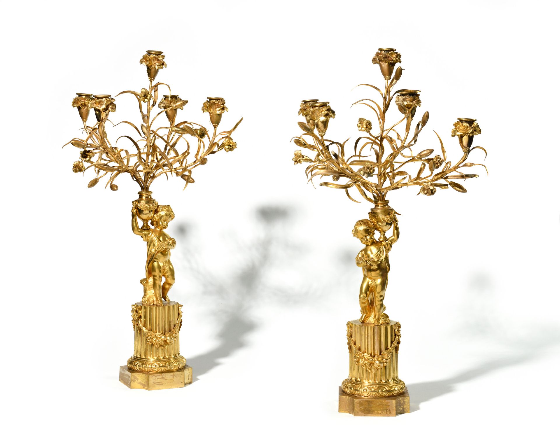Null 一对五灯臂烛台 
青铜镀金烛台，饰有一对普蒂，肩上扛着康乃馨花瓶。烛台立于带花环的凹槽圆柱底座上。 
路易十六风格，19 世纪。
高度：64 厘米