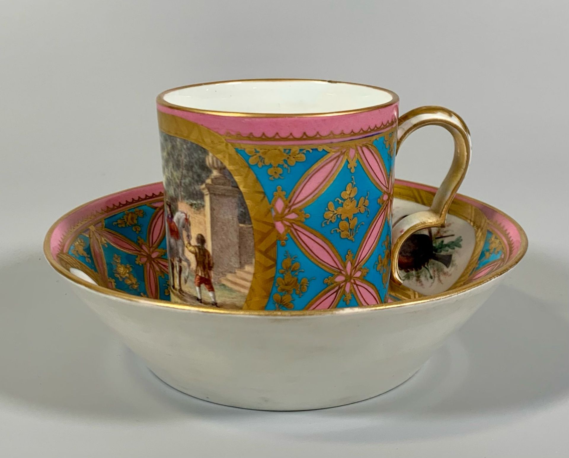 Null SEVRES
一件二等软质粘贴瓷杯碟，杯碟上饰有多彩图案，图案为粉色背景上以金色环绕的格子状底饰上的徽章中的生动场景，以及蓝色背景上的金色树叶和花环。&hellip;