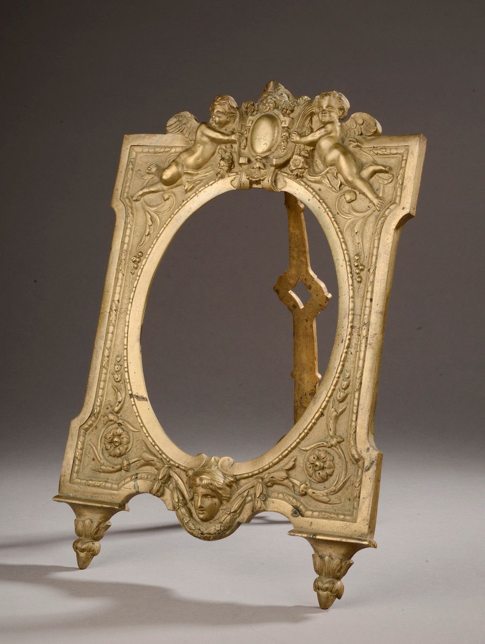 Null 
Una cornice in bronzo dorato (ossidazione), decorata con due putti che reg&hellip;