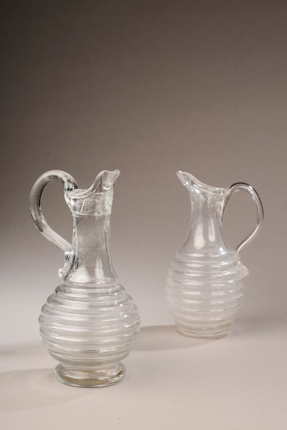 Null 两个吹制的玻璃杯，手柄是通过加热而形成的，杯身有环形。

诺曼底，18世纪。

高度。20.5和22厘米