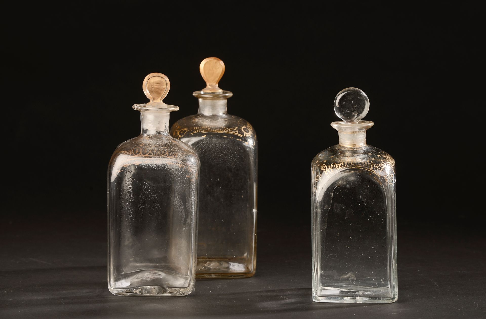 Null 三件吹制的方形玻璃瓶，肩部有镀金处理（三种尺寸，据说有瓶塞，镀金有磨损，一角有霜）。

18世纪。

高度17至18.5厘米