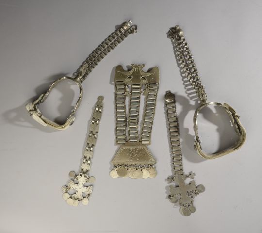 Null 一对金属马刺，有风格化的云朵雕刻装饰，有白色的皮革带（氧化，磨损）。

南美洲，19世纪。

长度: 20 cm



三个带链子和十字架的马匹金属装&hellip;