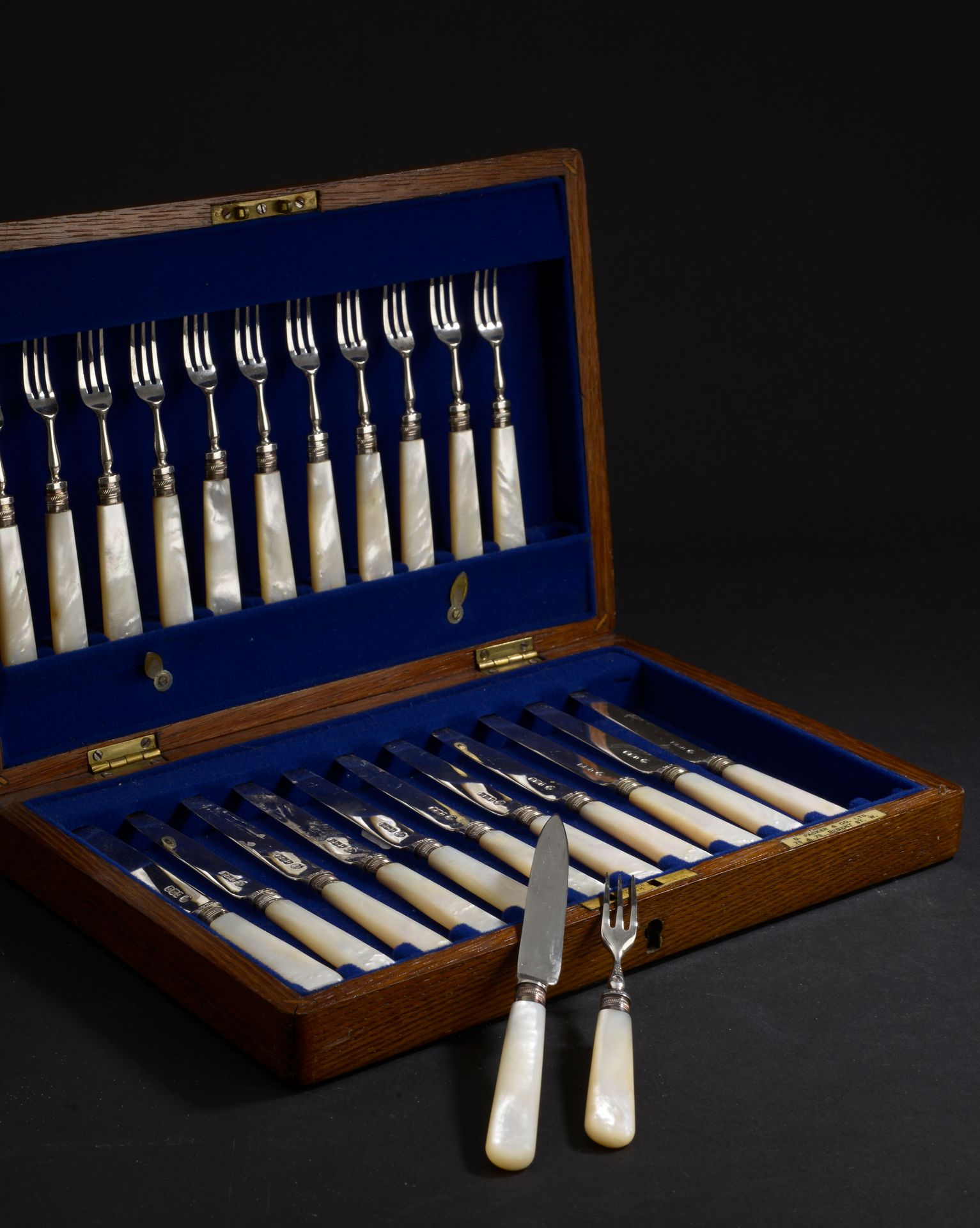 Null 一套12把刀和12把三叉甜点叉，刀片、叉子和卡套都是银的，手柄是白色珍珠母。

英国，谢菲尔德，1953年。

总毛重：828.8克

橡木箱，蓝色天&hellip;