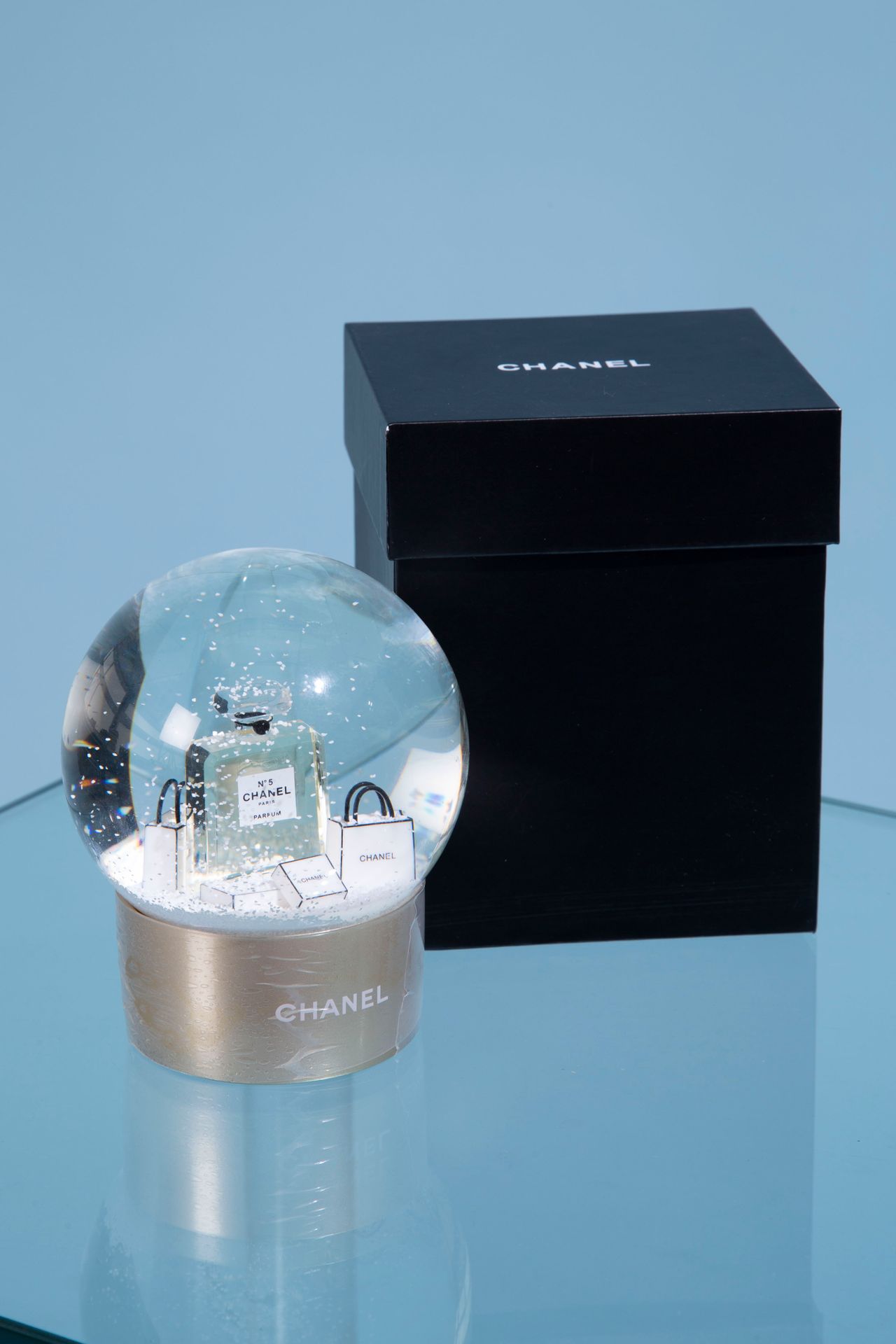 Null CHANEL. 

Glass snow globe on a gold lacquered plastic base featuring a bot&hellip;