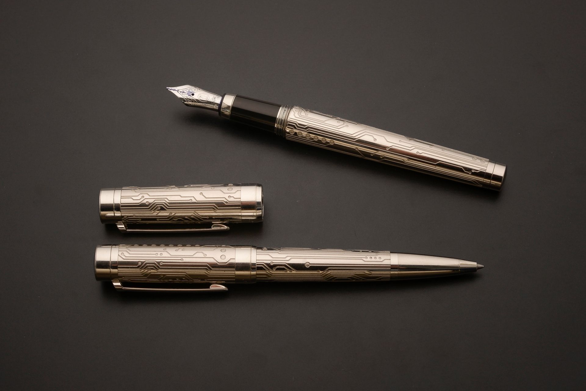 Null 卡地亚 "帕夏"。
套装包括一支钢笔和一支圆珠笔，笔身和属性为镀银金属，刻有电路，笔尖为18K白金D型切割，填充有笔芯。 
编号为103605（钢笔）&hellip;