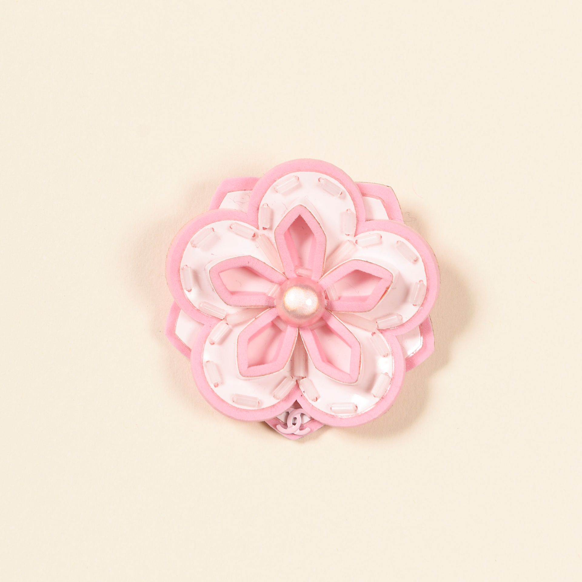 CHANEL. Pink plastic Camellia brooch centered with a fa…