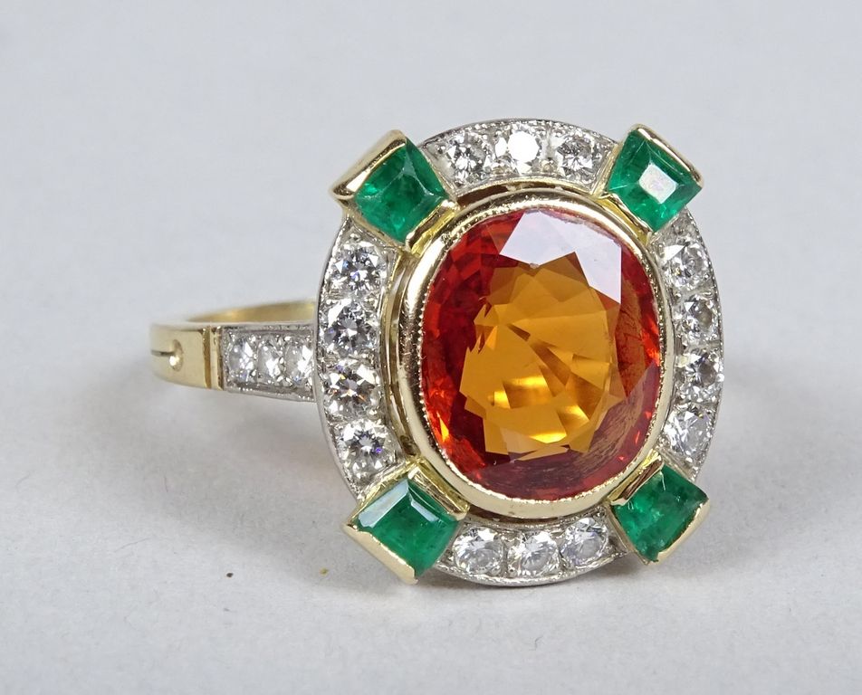 Null 宝石：18K黄金戒指，镶嵌一颗约2克拉的橙色蓝宝石，周围有20颗钻石和4颗绿宝石 P：6.7gr