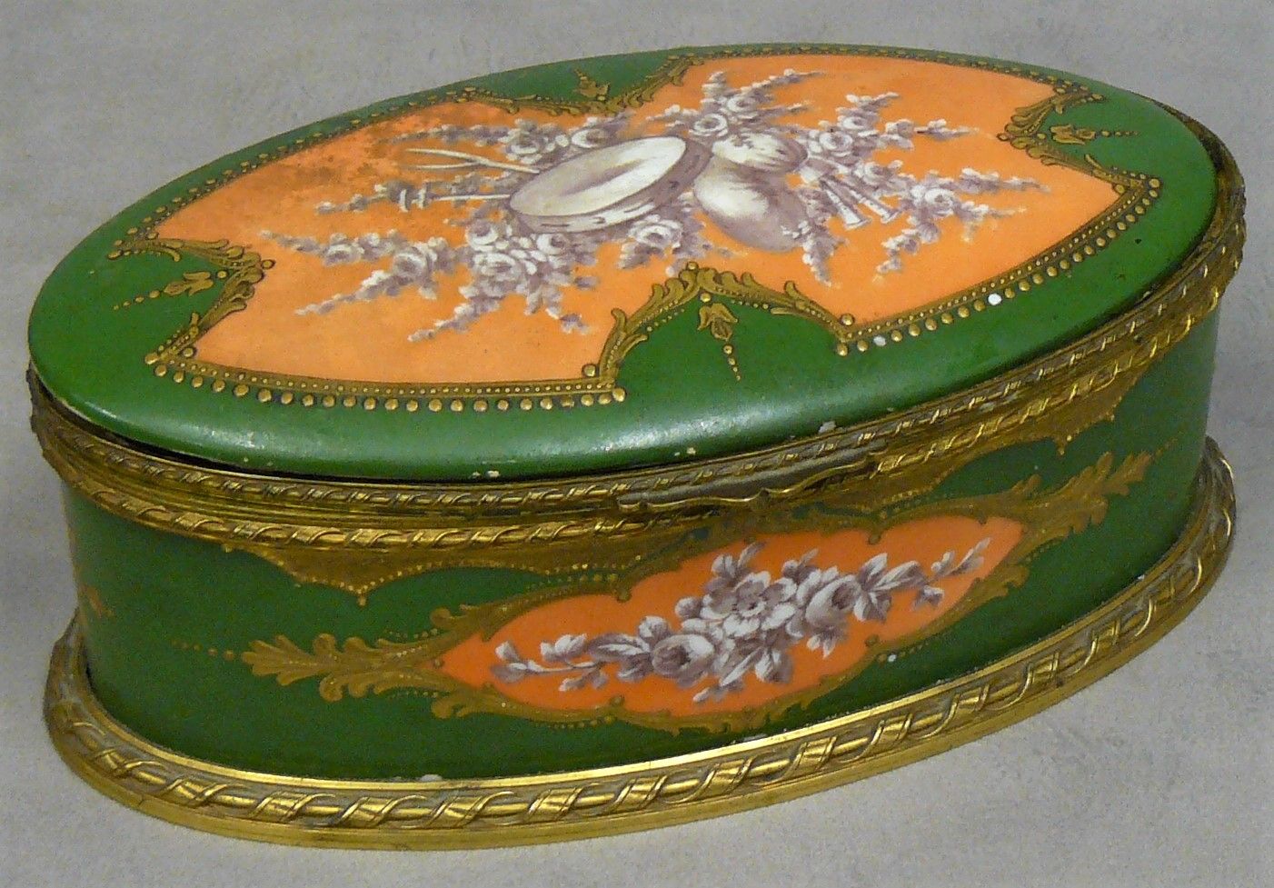 Null 路易十六风格的椭圆形瓷盒，绿色背景上的乐器和花朵，青铜安装（盖板松动） - 高8厘米，宽20厘米