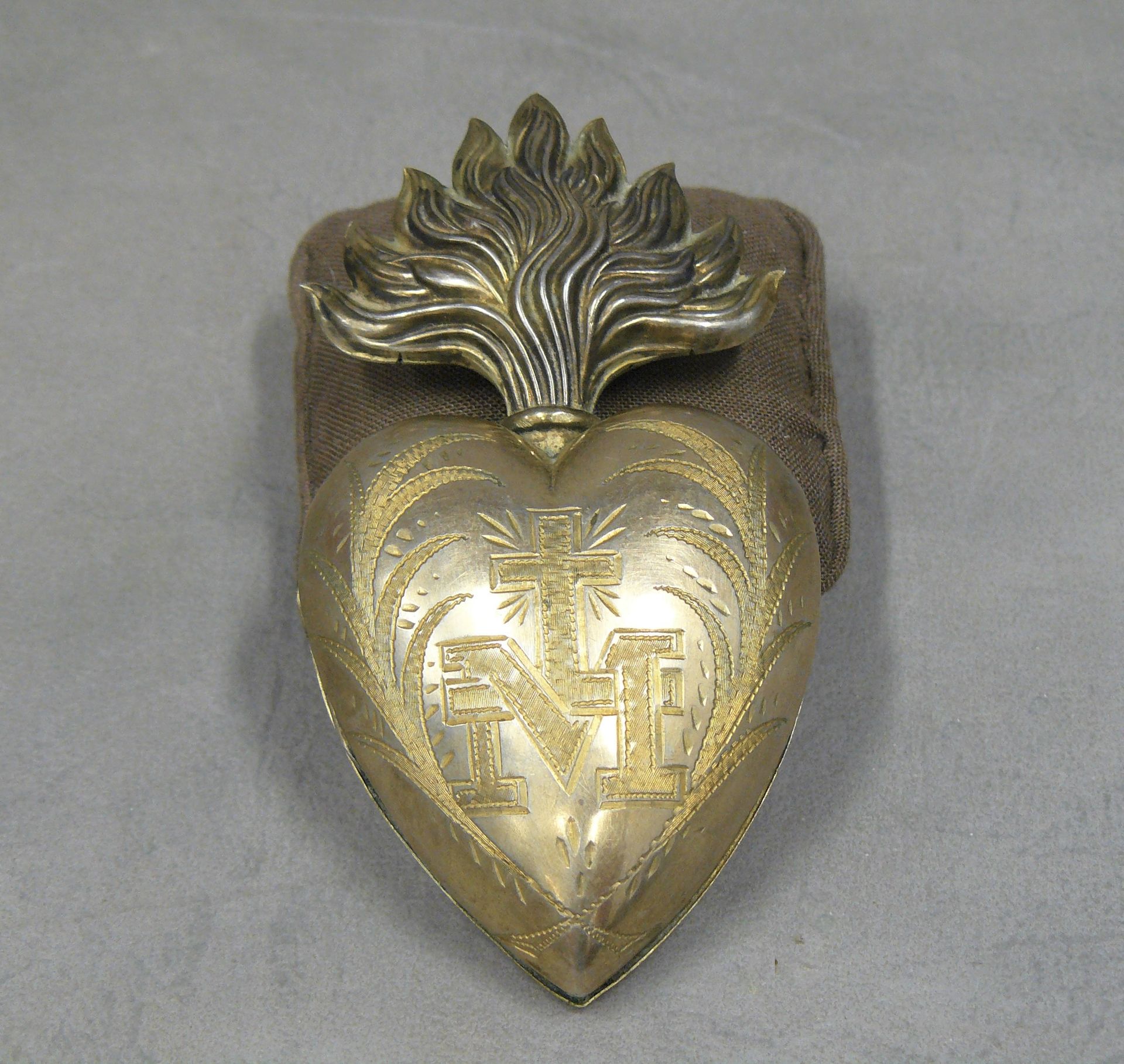 Null 一个银色和镀金的金属吊盒，形状是一个浮夸的心形开口，刻有字母M和一个十字架，用叶子做框架 11 x 5.5 cm
