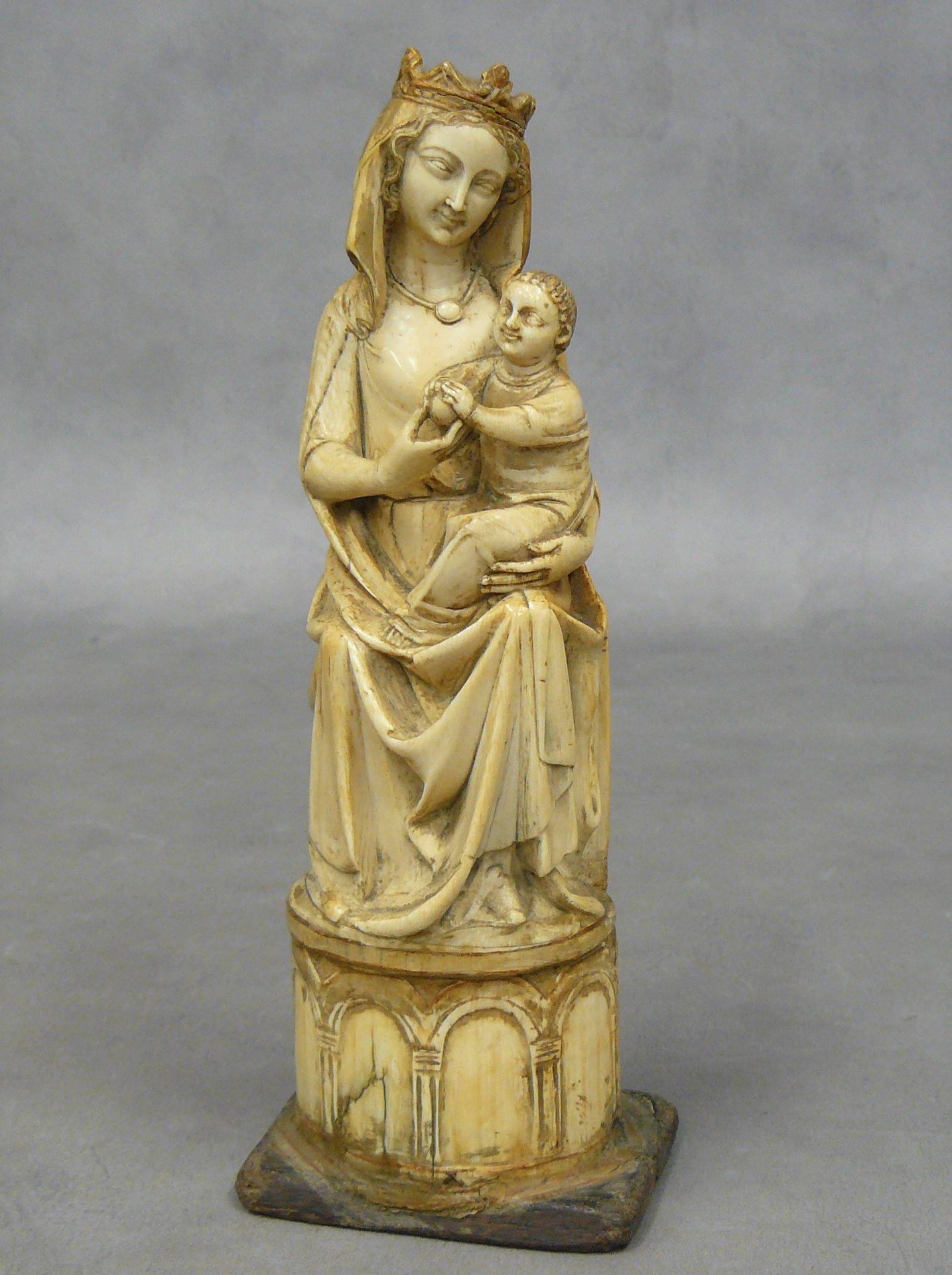Null 
圣母子：美丽的中世纪晚期象牙雕刻雕像，圣母坐在宝座上，她的孩子在她的左膝上，他们拿着一个苹果，宝座靠在一个有弧度的底座上 - 高23厘米
