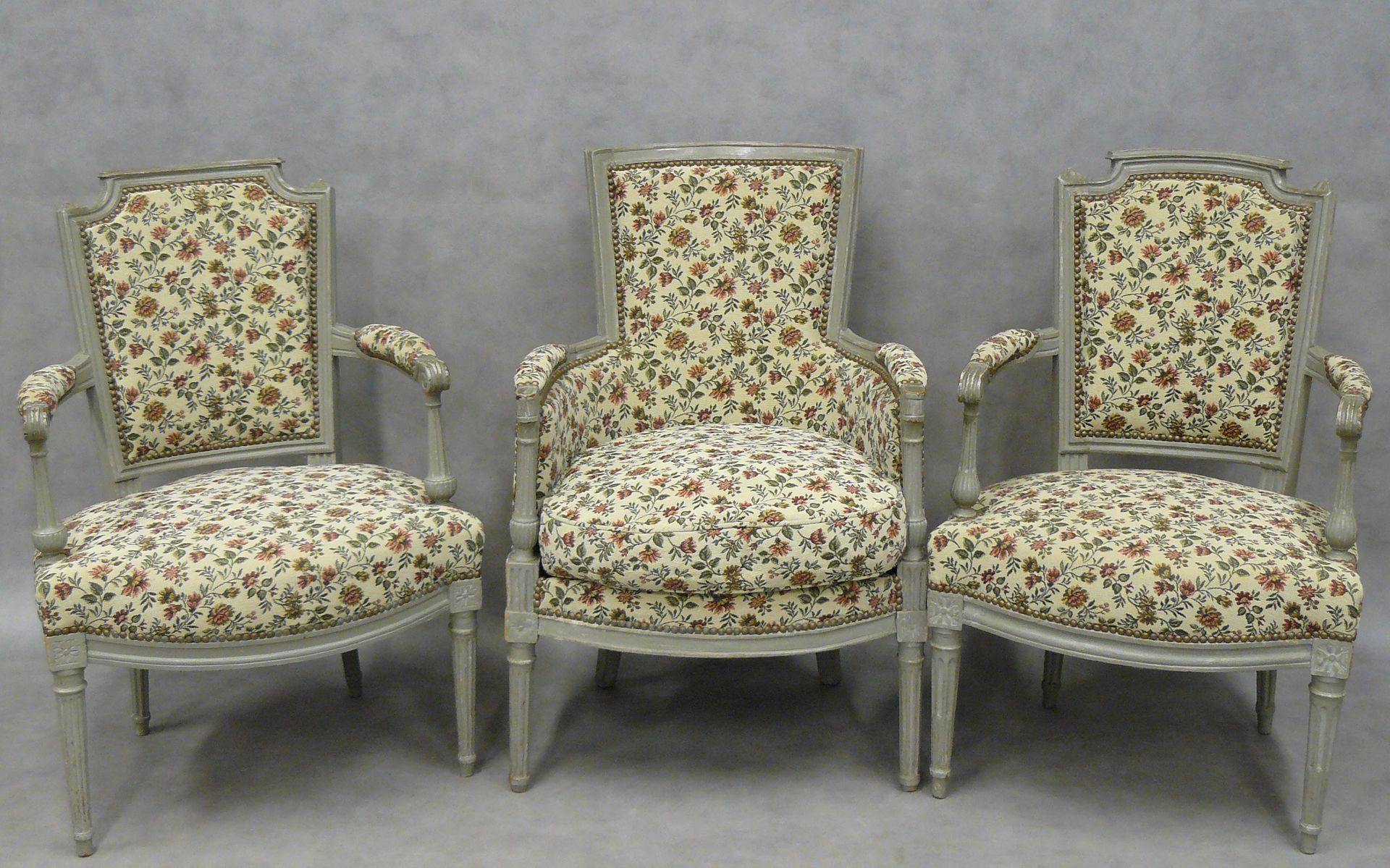 Null un sillón y dos cabriolés estilo Luis XVI lacados en gris, tapicería floral