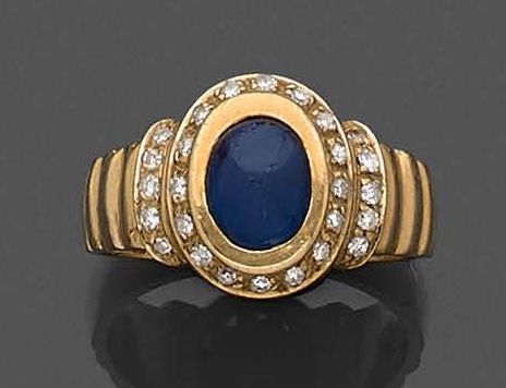 Null 黄金（750‰）Godronné戒指，镶嵌椭圆形凸圆形蓝宝石，周围和肩部镶有明亮式切割钻石。
指头：55 - 毛重：8.5克