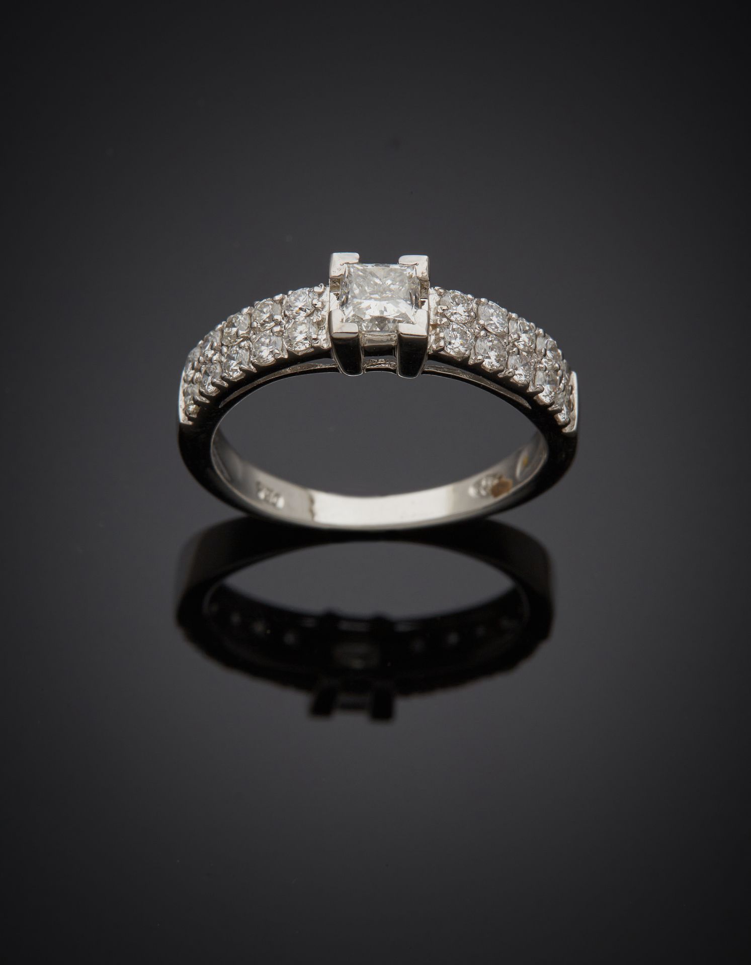 Null 一枚白金戒指（750‰），镶嵌着一颗公主式切割的钻石，重约0.5克拉，并镶嵌着排列整齐的明亮式切割钻石。
指头：54 - 毛重：3.5 g