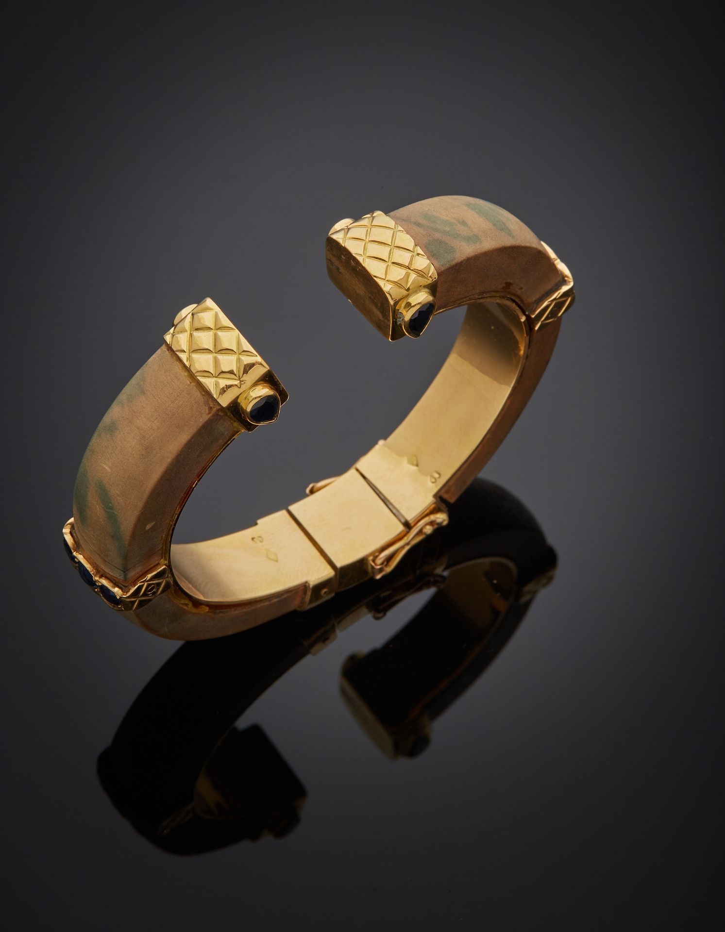 Null 黄金(750‰)绗缝开口刚性手镯，镶有梨形和圆形蓝宝石，复合装饰有木头（破裂和脱落）。
(意外的是扣子)。
长度：15厘米约
毛重：45.1克