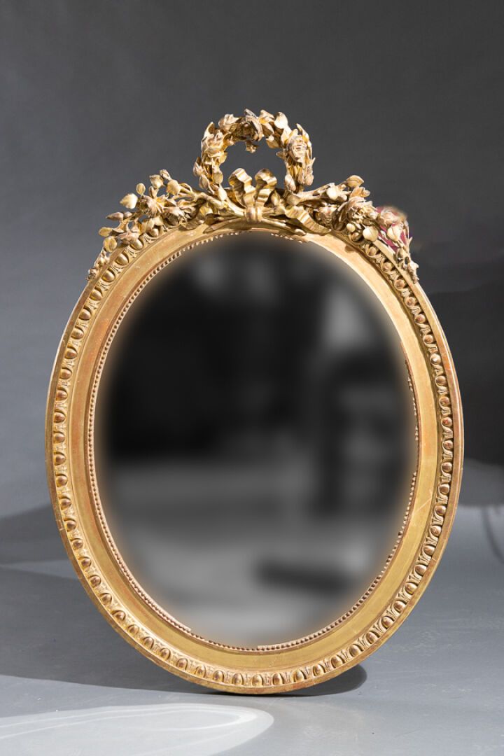 Null Miroir ovale en bois mouluré, stuqué et doré à la feuille d'or à décor d'un&hellip;