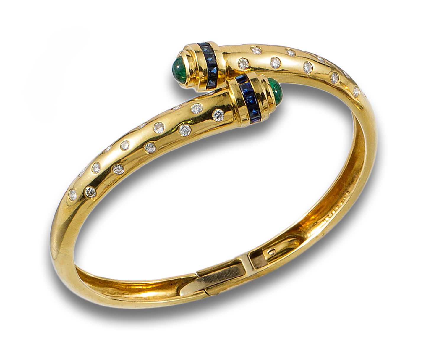 18 kt yellow gold torque bracelet. 由两端的凸圆形祖母绿、一排校准的蓝宝石（其中一颗缺失）和一个点缀着明亮式切割钻石的夏顿镶嵌&hellip;
