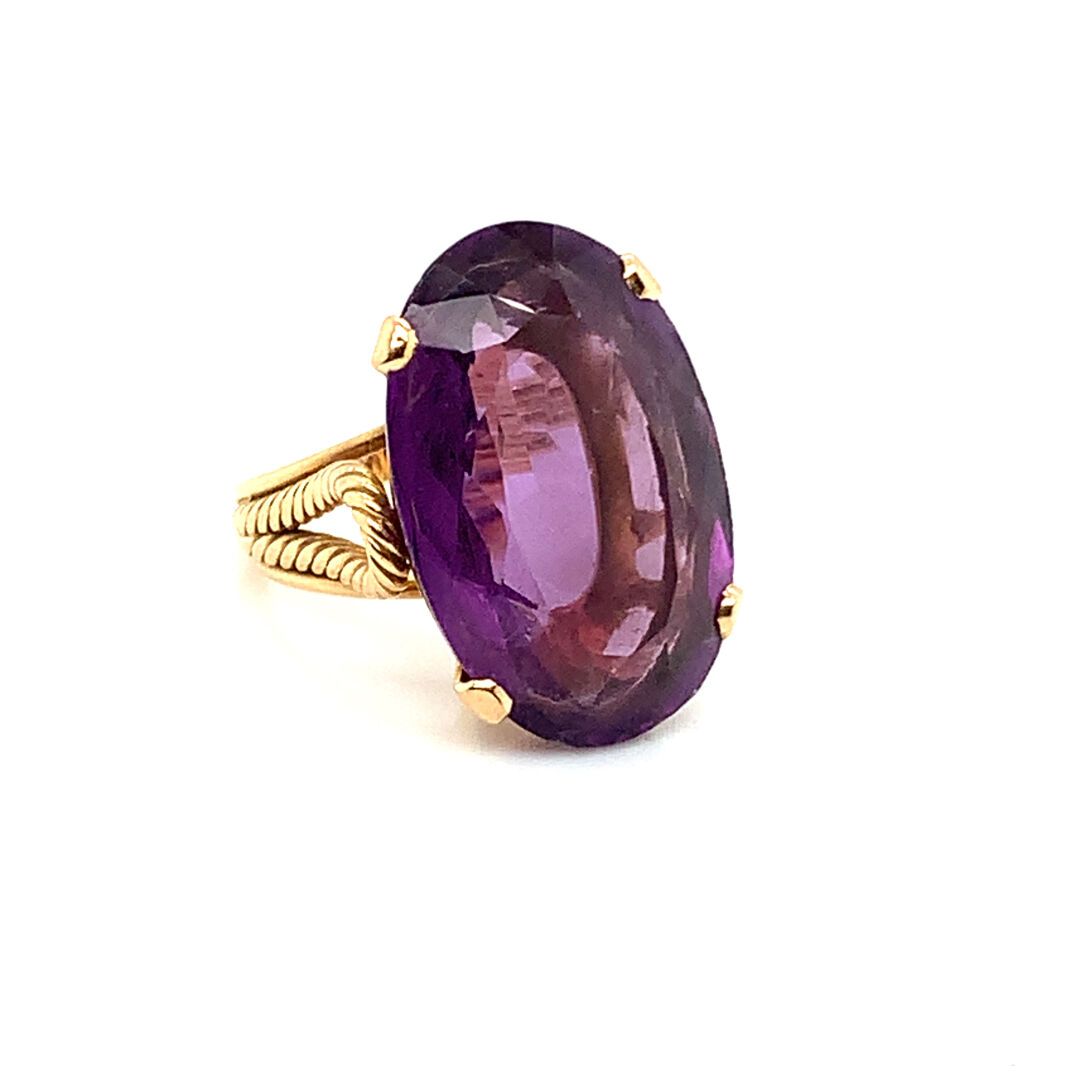 BAGUE en or et améthyste 金戒指(750‰)，镶有一颗大的椭圆形刻面紫水晶。
毛重：10.36克。手指大小：54
(叶子上有小缺口)
