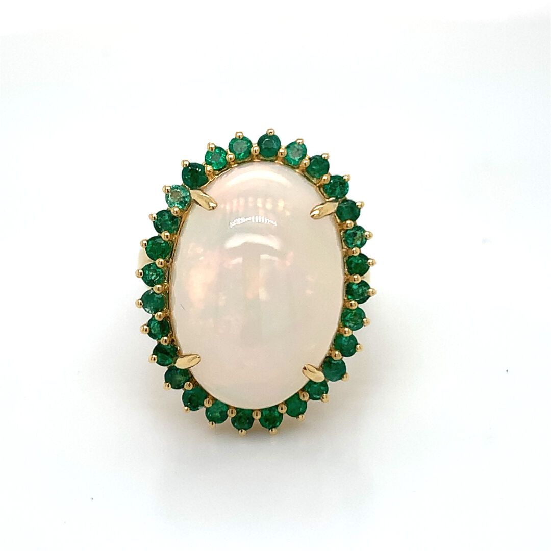 BAGUE en or, opale et émeraudes 金戒指（750‰），在一圈明亮式切割的祖母绿中，用爪子镶嵌了一颗大的椭圆形凸圆形蛋白石。
毛重：&hellip;