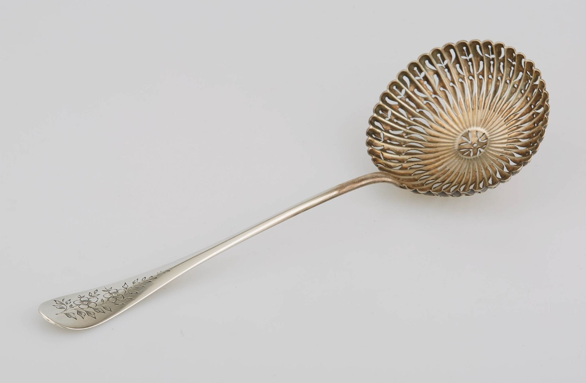 Null 银质洒水勺，圆形穿孔勺，长方形图案刻有花茎。米纳瓦标记。M.O.: CARON。长度：19.5厘米。重量：46克。
