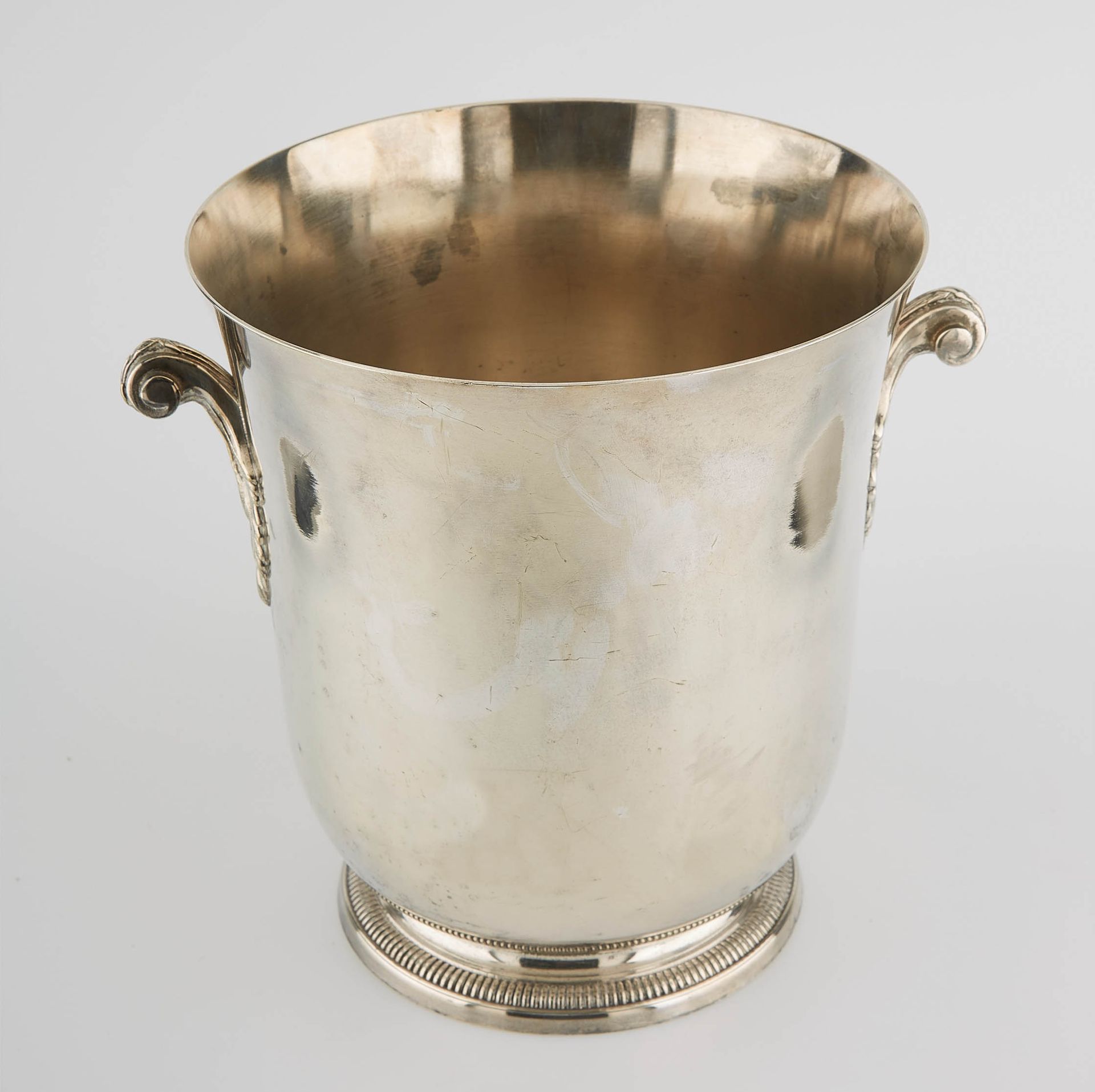 Null ERCUIS。镀银金属的香槟桶放置在一个圆形的基座上，有带叶子的模制把手。高度：23厘米。高度：23厘米。直径：20.5厘米。