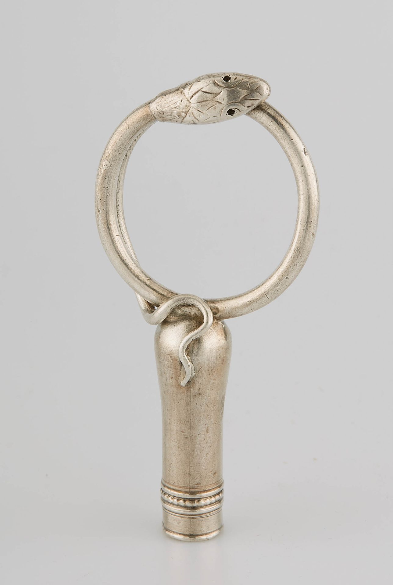Null 
一根镀银的手杖或阳伞柄，握柄处有一条蛇，环状物可作为手套架。19世纪。9,5 x 4,5厘米。