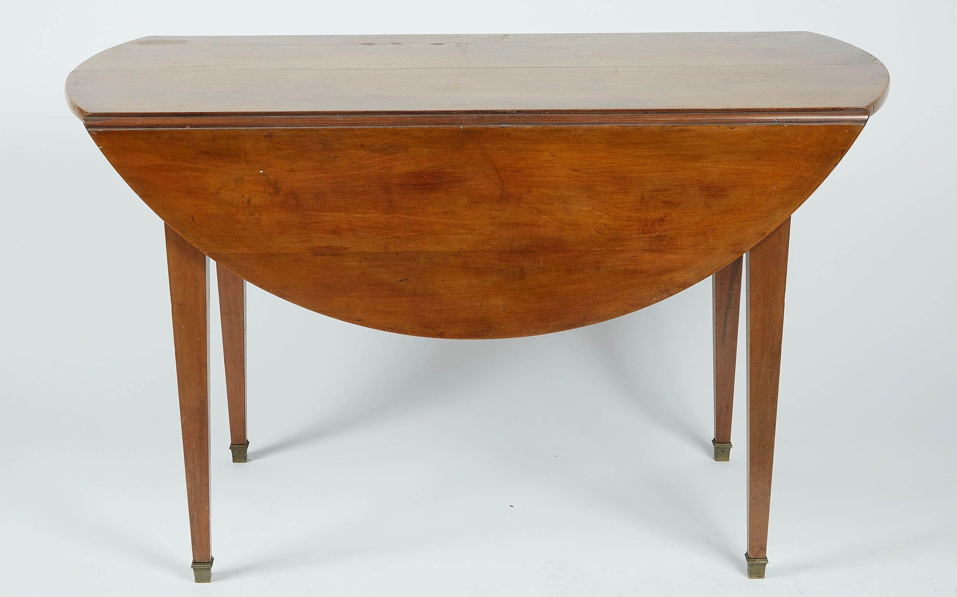 Null A round mahogany veneered table with flaps, standing on four sheath legs fi&hellip;