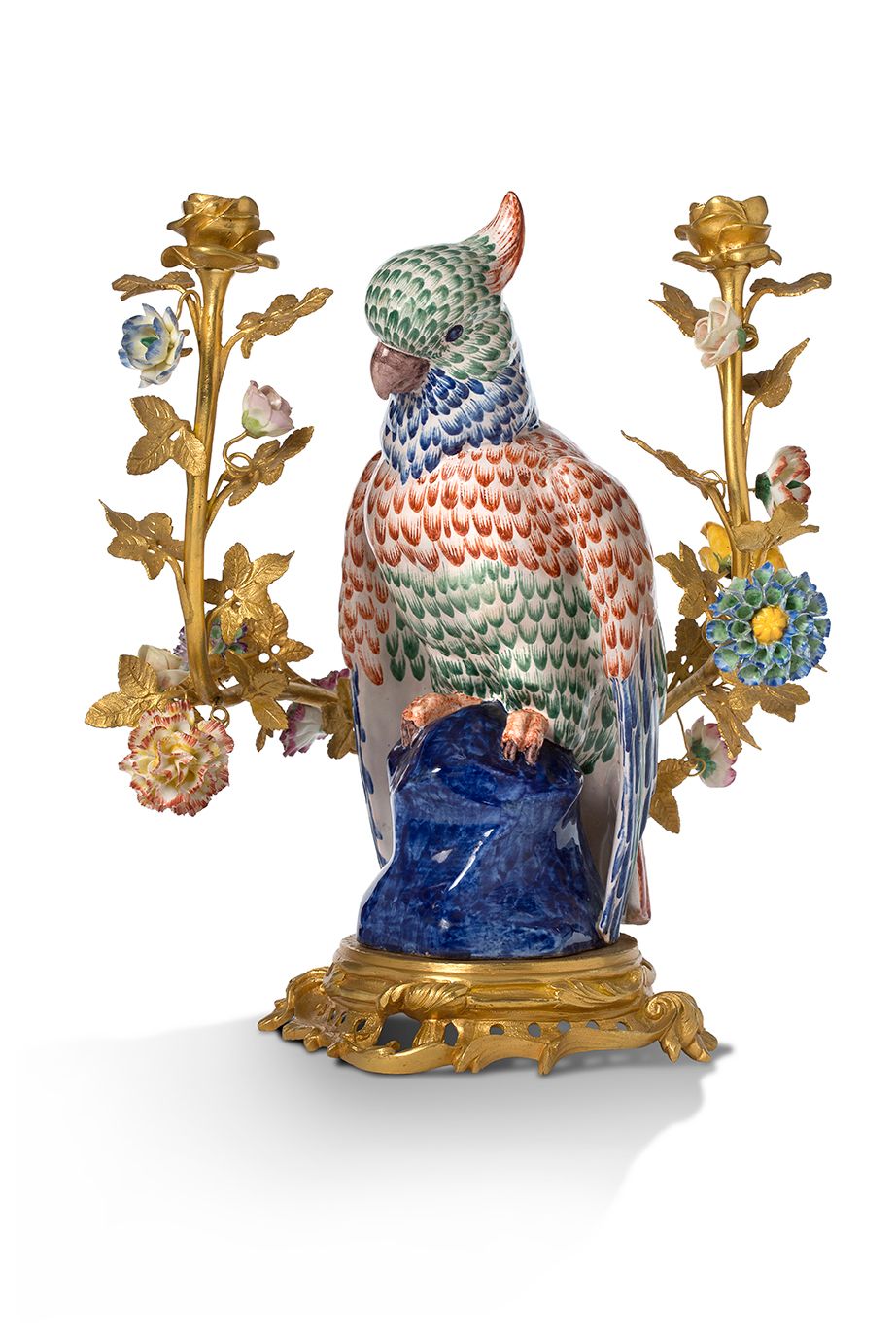 Null 一个双灯鎏金铜烛台，装饰有多色陶制鹦鹉和多色瓷制花朵。底座是弯曲的。
18世纪的风格。
高36，宽30厘米
 （小事故和缺失的部分）。