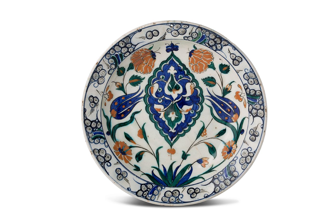 [IZNIK] 
一个硅质陶瓷 "tabak "盘，上面有一个曼陀罗，在白底上用美丽的多色和红色的滑石装饰，曼陀罗在蓝底上，周围有康乃馨和郁金香。
边缘上有风格&hellip;