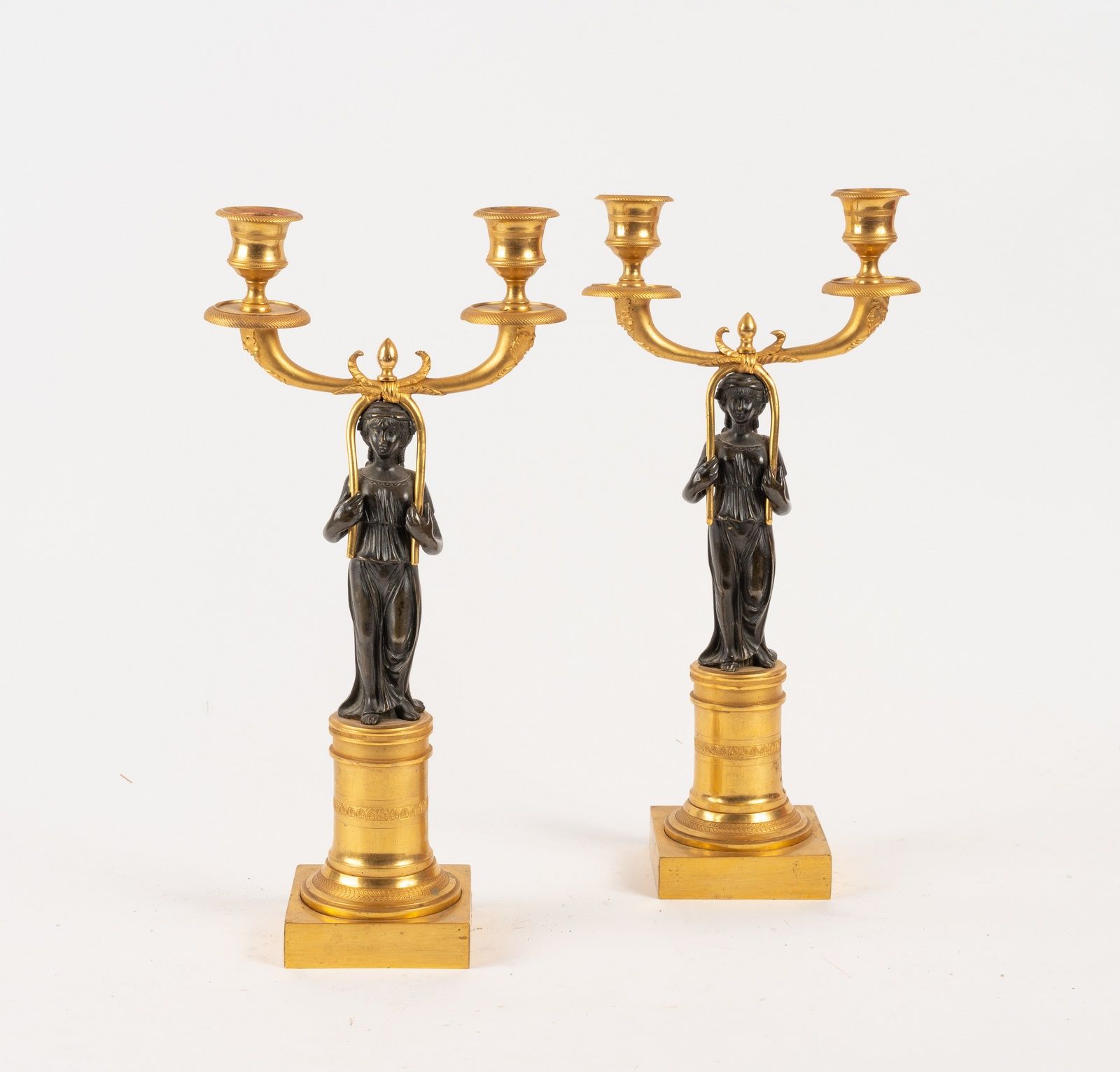 Null 一对木制和抛光的青铜烛台，装饰有古董妇女，拿着两个灯臂，靠在装饰有棕榈和叶子的楣的柱子上。
帝国时期
高度：35.5厘米
