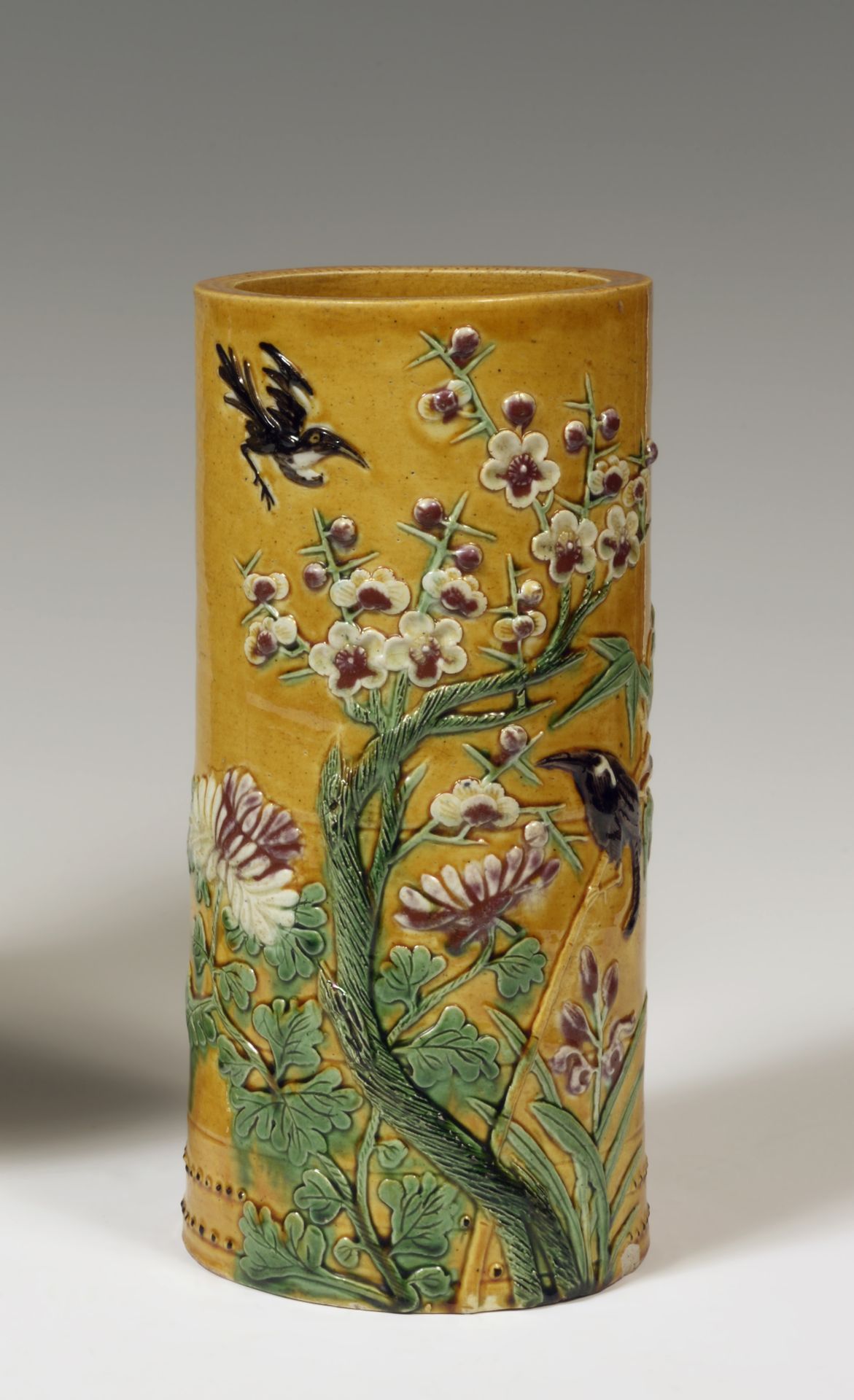 Null 
中国

黄、绿、黑、褐四色珐琅彩圆柱形花瓶，有鸟、梅花和牡丹的浮雕装饰。

19世纪。 

H.27厘米。

基地上的芯片。