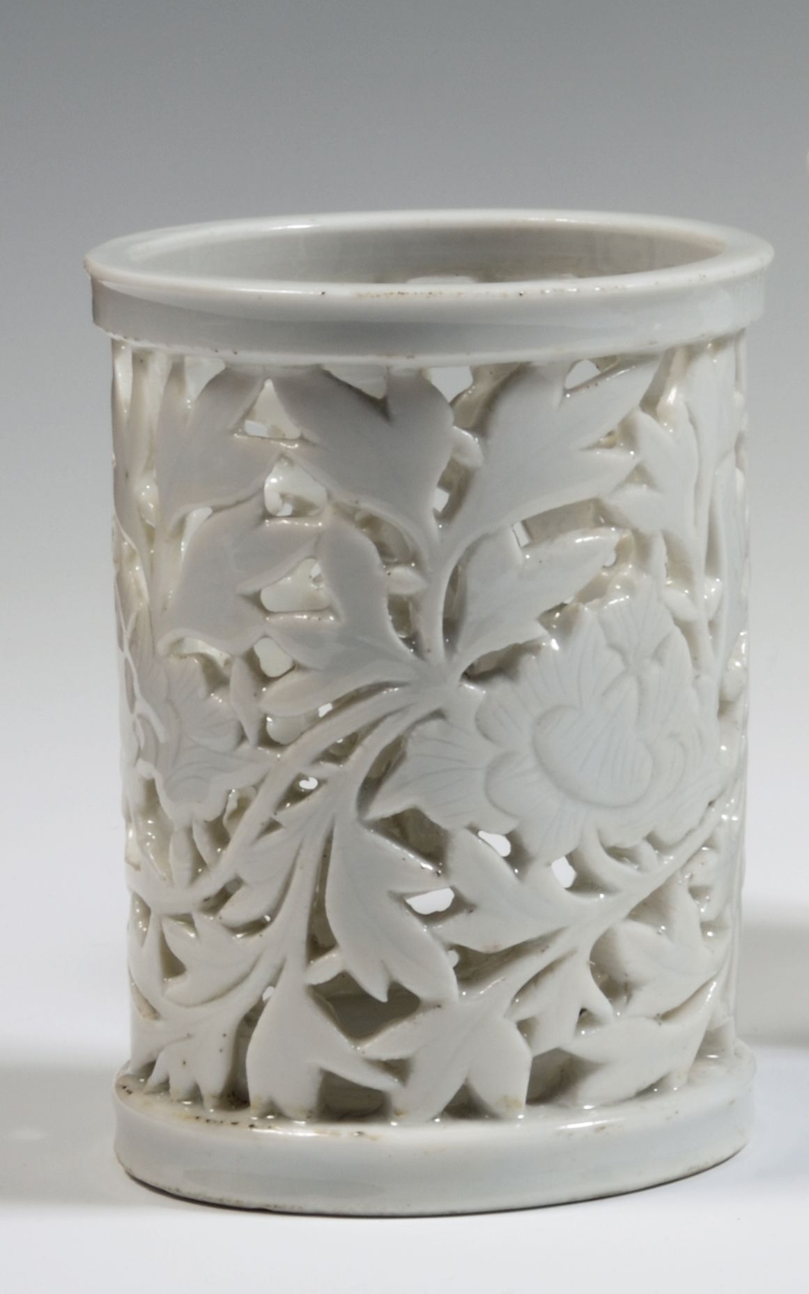 Null 
中国

一个中国白瓷圆柱形笔筒，壁上有镂空的牡丹和叶子，另一个有几何图形的图案。

17-18世纪。 

H.13厘米。