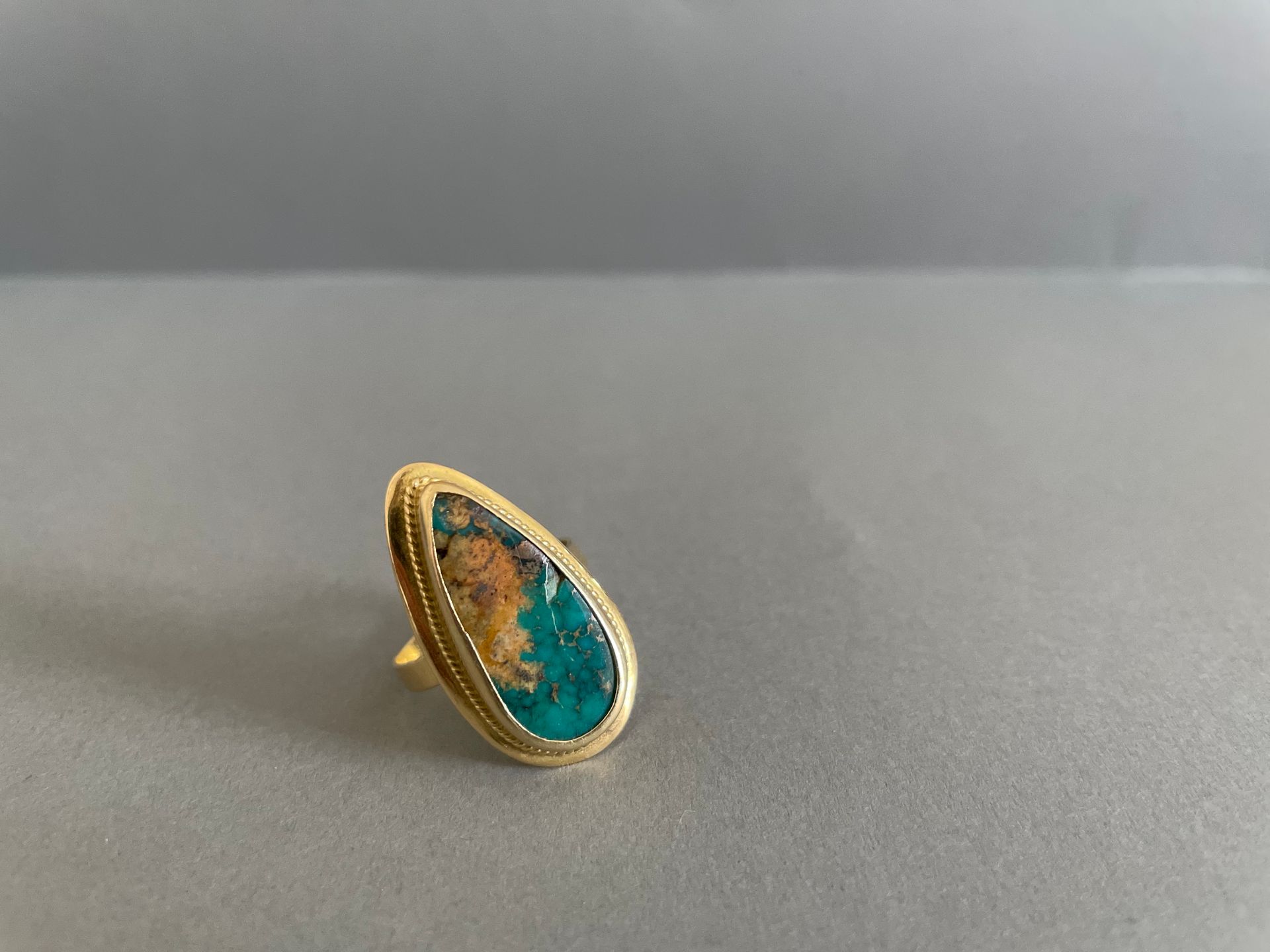 Null Ring besetzt mit einer Türkis-Piriform (Acc.) 

Fassung aus Gelbgold.

Brut&hellip;