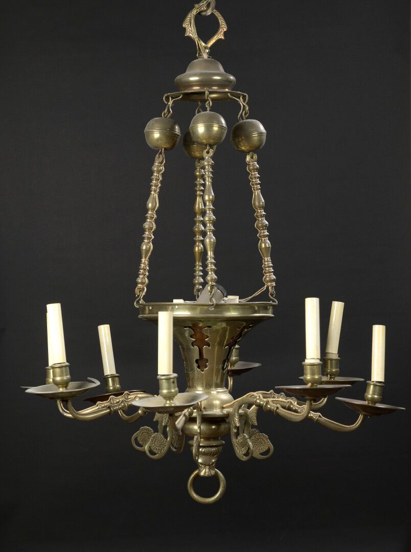 Null 黄铜吊灯，喇叭形的轴由四个栏杆链和环支撑，支持八个滚动的光臂。

17世纪风格

身高：103厘米