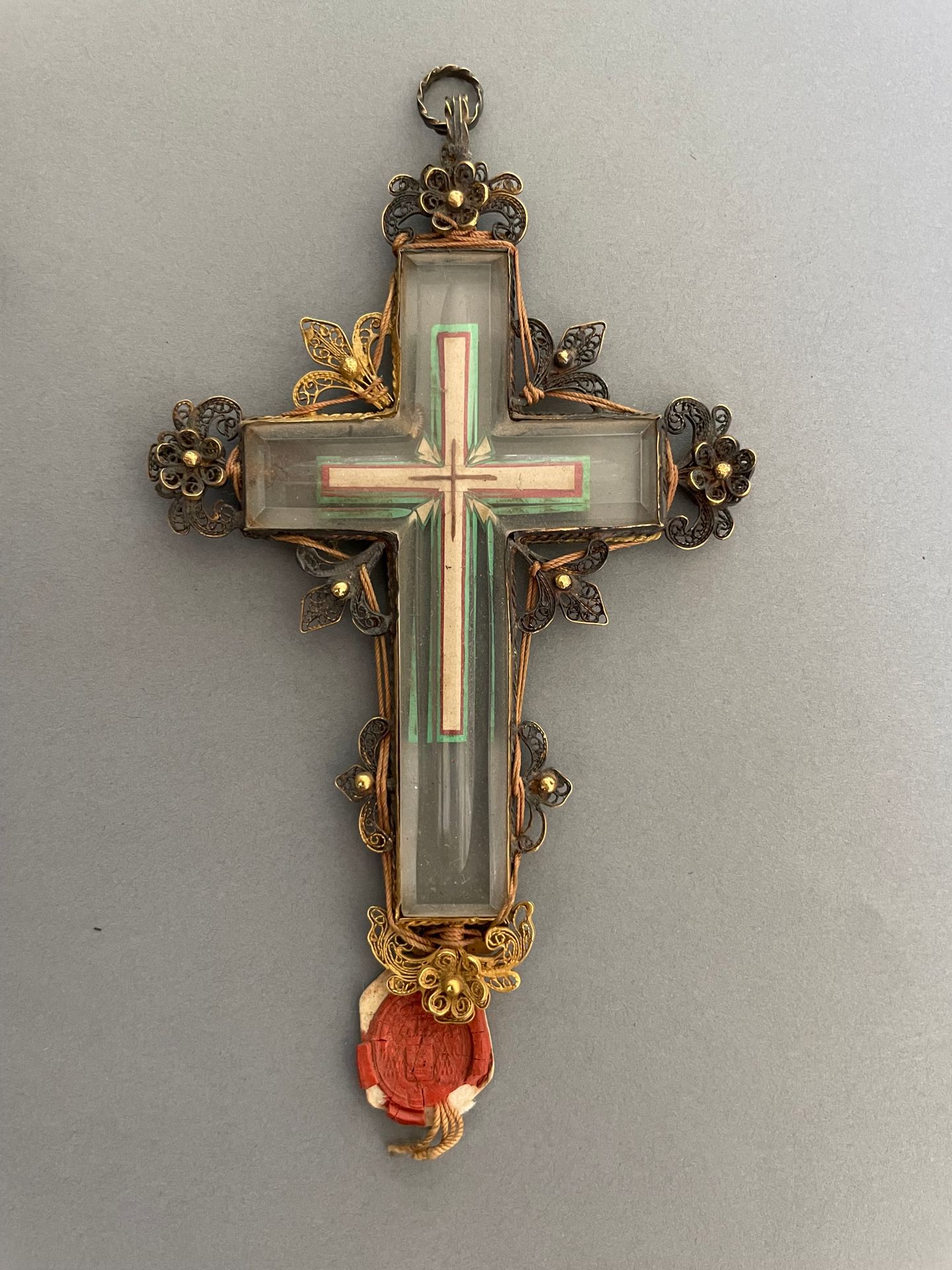 Null 一个水晶十字架吊坠，上面有游丝花纹图案，是vermeil材质的。 
带有红衣主教纹章的蜡封。 
时期：19世纪初
H.10厘米
在它的箱子里。