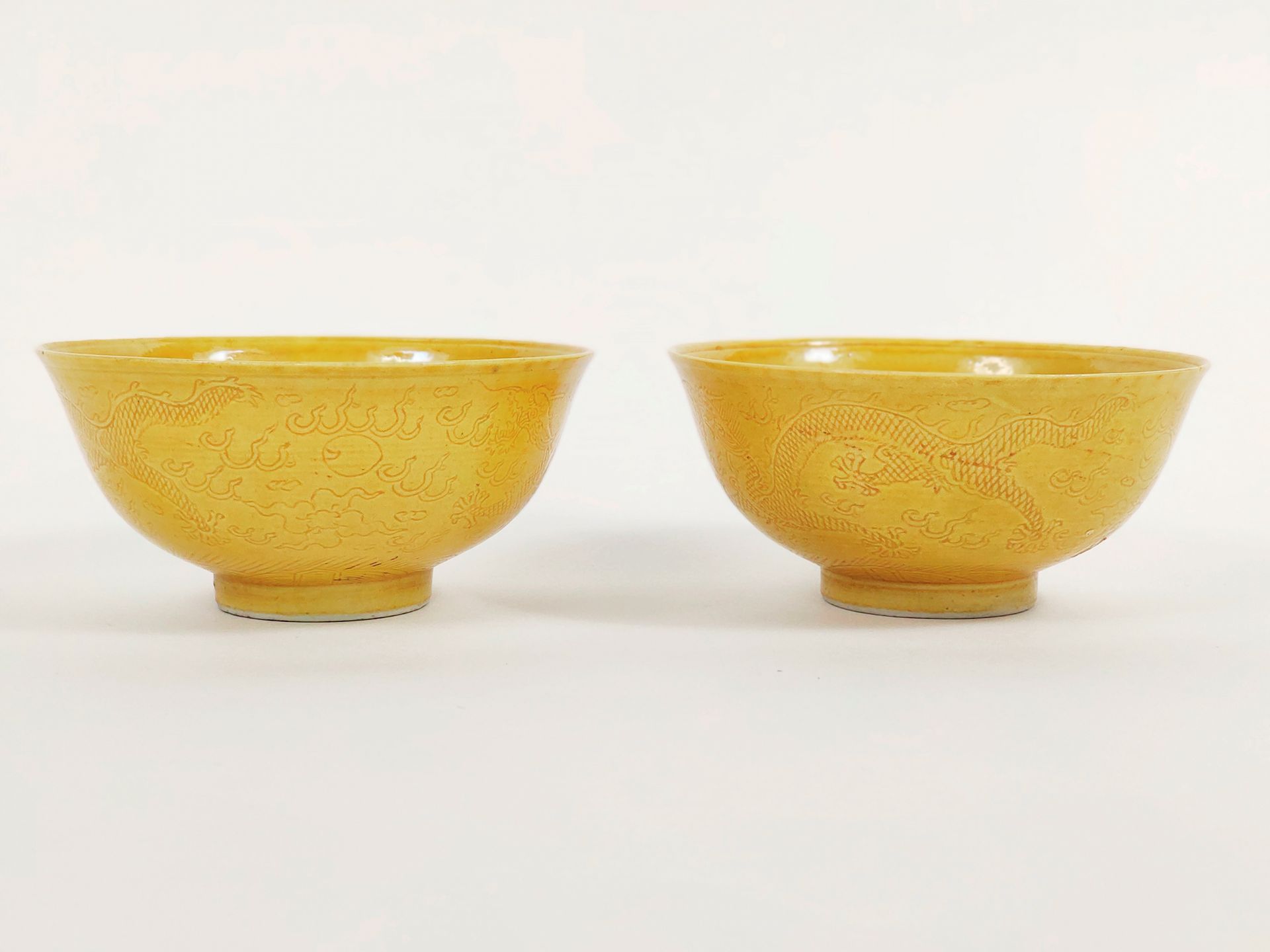 CHINE - EPOQUE KANGXI (1662 - 1722) 
一对黄色珐琅彩瓷碗，外面刻有二龙戏珠的图案，里面是龙的保留。底座反面有釉里红的康熙六字&hellip;