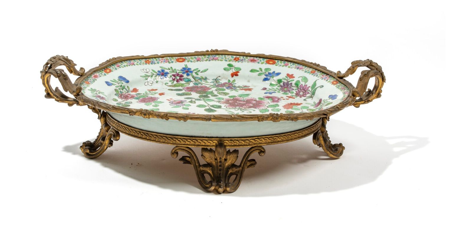 CHINE - Vers 1900 
瓷盘上装饰有粉彩风格的牡丹花，边缘装饰有造型花卉的楣。青铜支架
长41厘米
不保证支架下的瓷器状况。