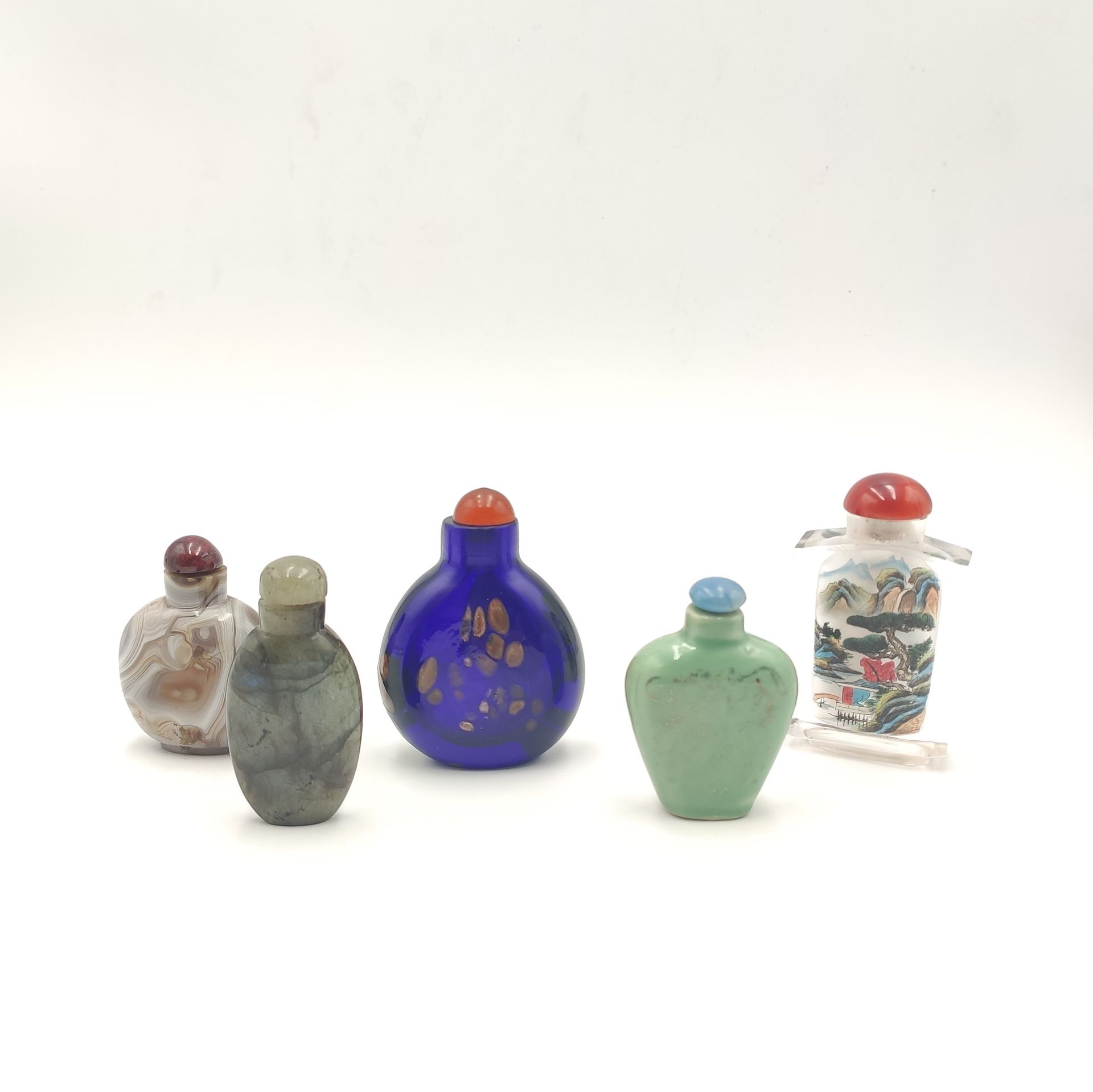 Null 一套五个鼻烟壶，其中两个是由硬石（拉布拉多石和玛瑙）制成的，一个是模仿砂金石的蓝色玻璃，一个是抹金的绿色玻璃，还有一个是有风景图案的玻璃。