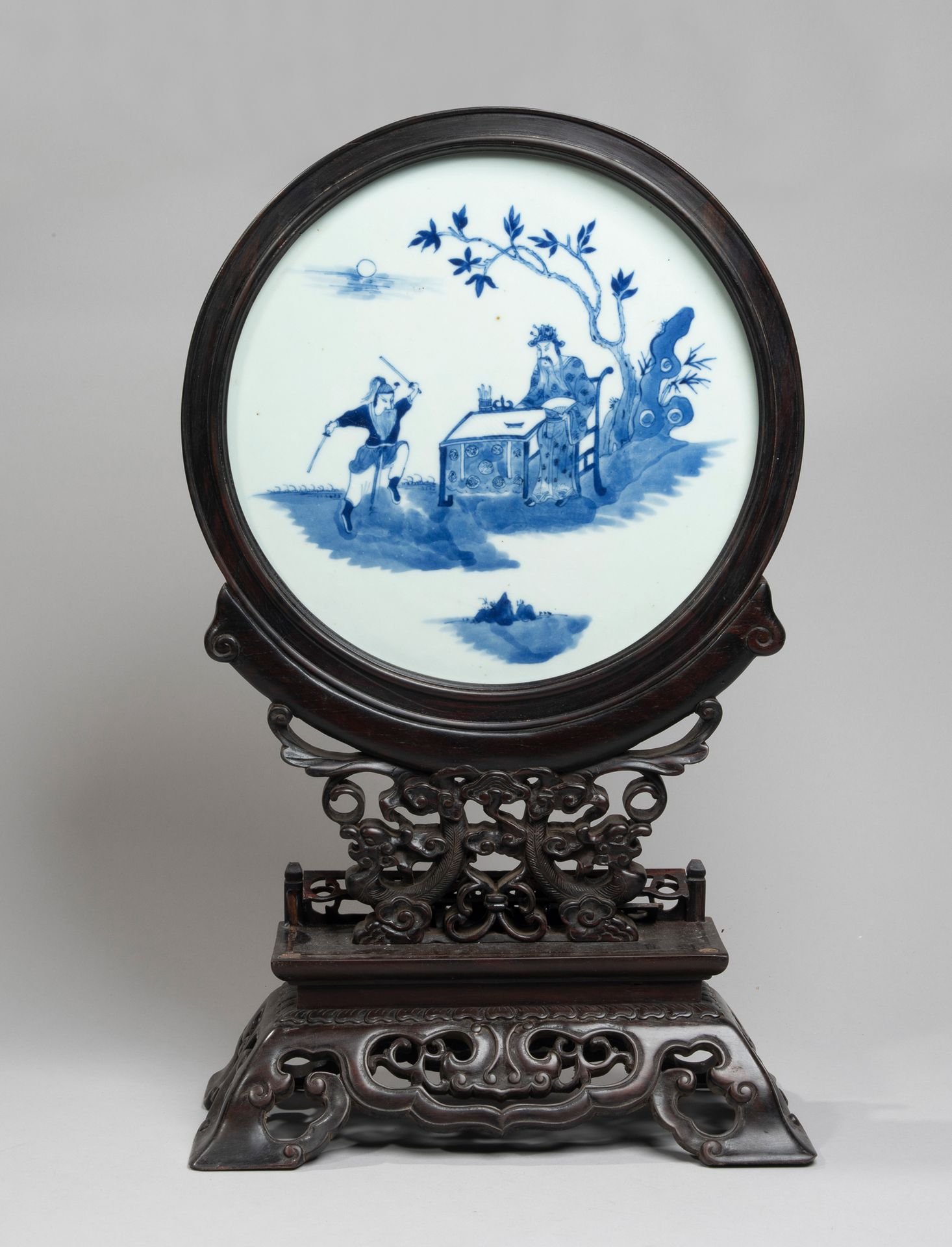 VIETNAM, Hue - XIXe siècle 
釉下青花圆形瓷盘，上面有一个坐在桌前的学者和一个武士的图案，装在一个雕有凤凰的双围屏上。(缺少栏杆)
直&hellip;