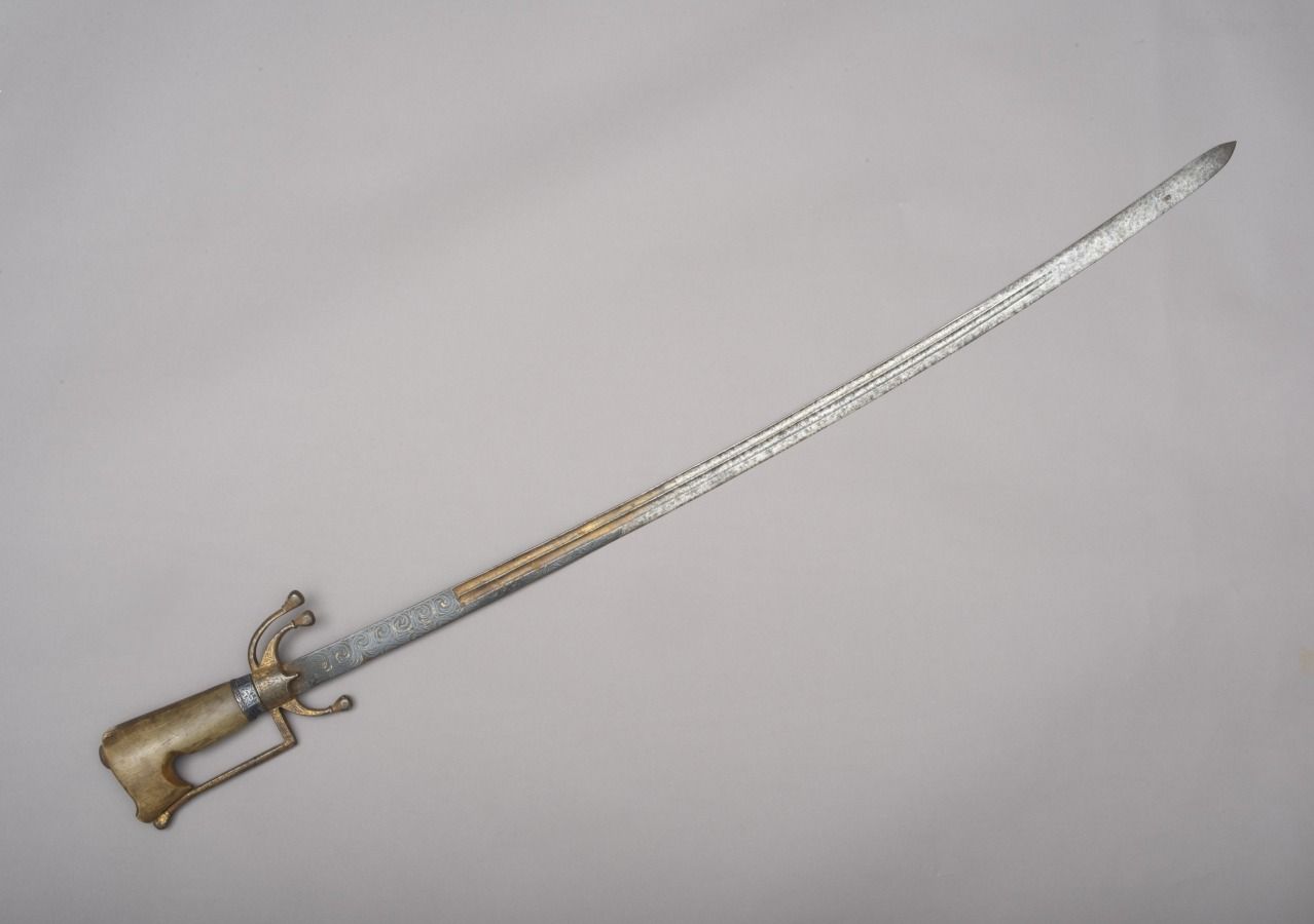 Null 尼姆查

摩洛哥，18-19世纪

长102.5厘米

这款摩洛哥尼姆查有一个略微弯曲的单刃钢刀，有很深的沟槽。

典型的手柄有一个角质的手柄，有一个&hellip;