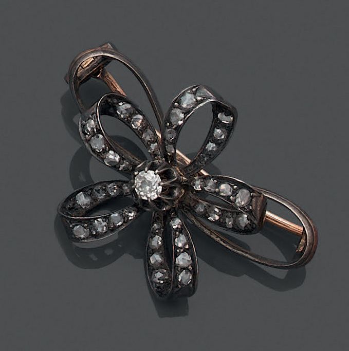 Null 18K（750）黄金和925银胸针，以蝴蝶结为特色，五个环状物饰有玫瑰花，并由一颗老式切割钻石连接。
毛重：7.56克。