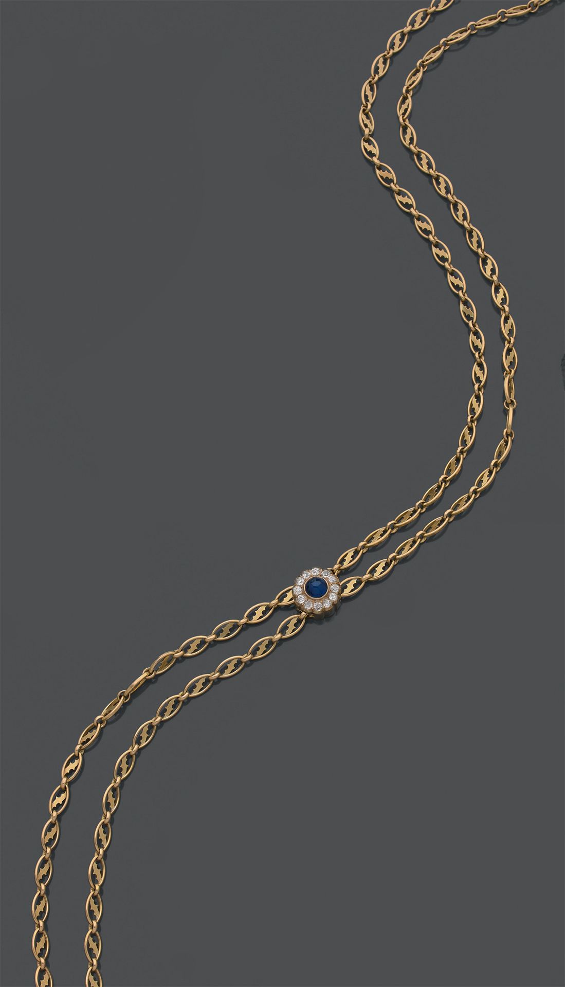 Null 18K(750)黄金长项链，穿有不对称风格图案的脐带环，镶嵌一颗凸圆形切割蓝宝石，周围有12颗老式切割钻石。19世纪。
毛重：74.84克。
长度：1&hellip;