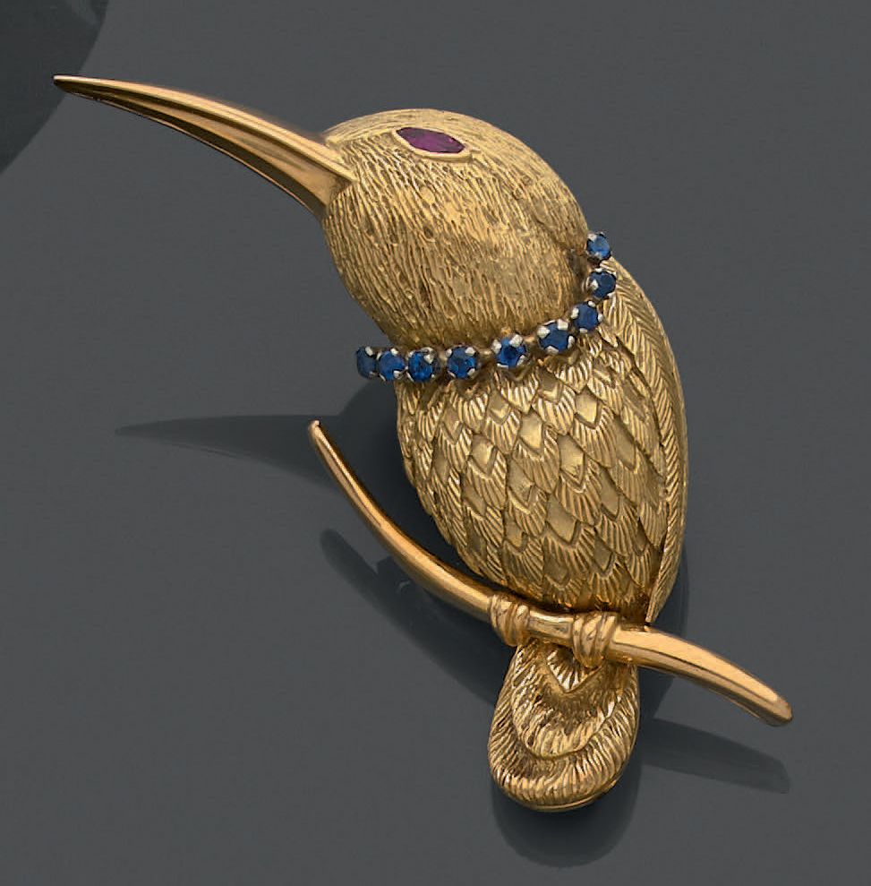 Null 18K (750)黄金和白金胸针，雕琢出一只自然的蜂鸟，停在树枝上，眼睛镶嵌着一颗脐带红宝石，脖子上有一串小蓝宝石项链。
总重量：22.64克。