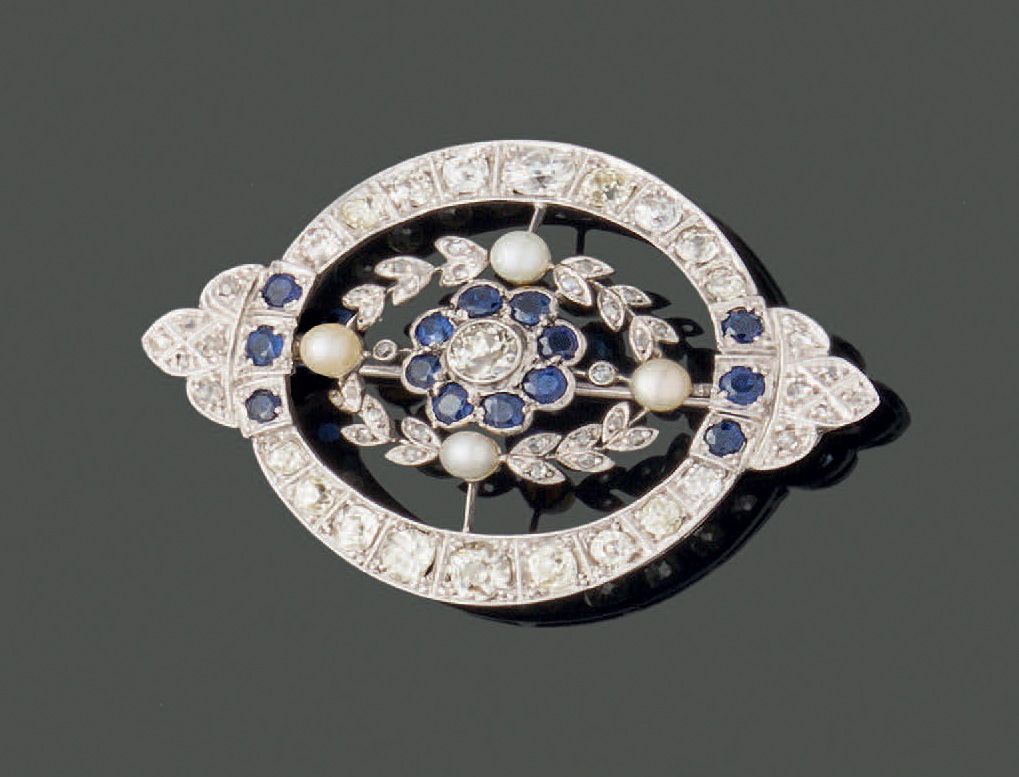 Null 
18K（750）白金和铂金圆形胸针，由两个镶嵌老式切割钻石的月牙组成，中间穿插着两个三重蓝宝石，肩部是镶嵌玫瑰切割钻石的三叶形图案。在中央，一颗老式&hellip;