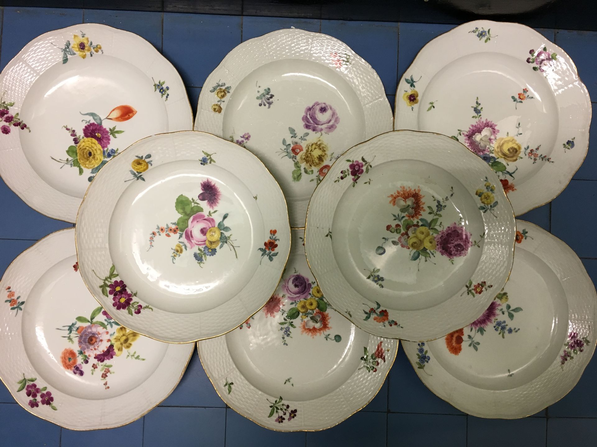 Null ALLEMAGNE. 19 assiettes rondes en porcelaine, décor floral, bordure à motif&hellip;