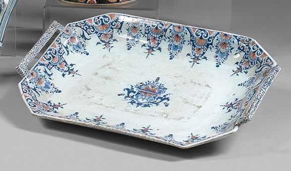 ROUEN 长方形盘子，有两个把手，陶器称为 "banette"，用蓝色和铁红色的羊角花装饰，框住了一个带叶子的花篮。18世纪前三分之一（边缘有裂缝，手柄卡住）&hellip;