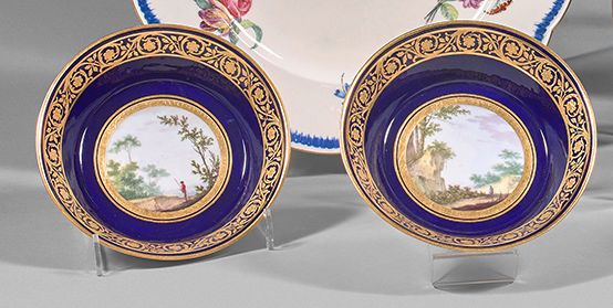 SÈVRES 一对软瓷碟子，装饰着一个在蓝色背景上有金色花环装饰的树木的风景人物。反面有两个交错的L的标记，还有一个是镀金师Le Guay（1751年至1797&hellip;
