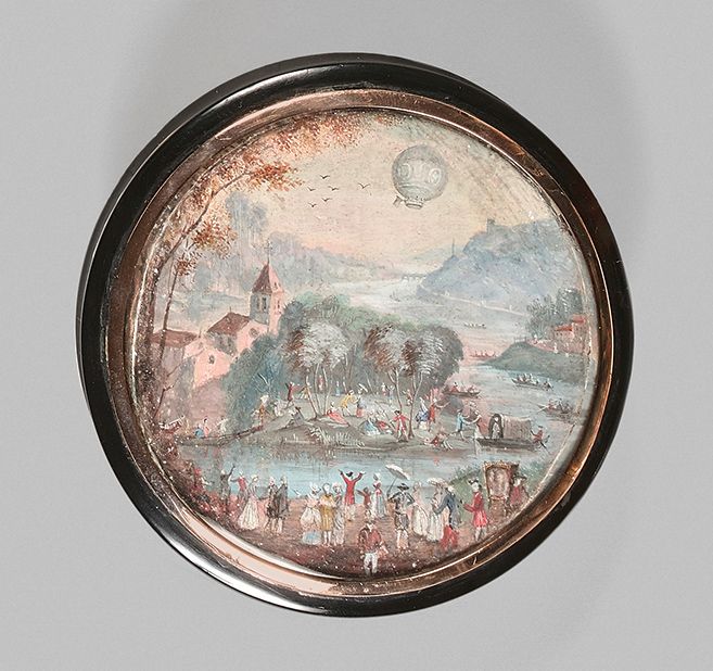 Null 一个圆形的棕色玳瑁盒，盒盖上镶嵌着一个画在纸上的圆形微型画，画的是一个热气球从热闹的河边的法国村庄上空经过。湿度的痕迹。
，18世纪末或19世纪初的微&hellip;