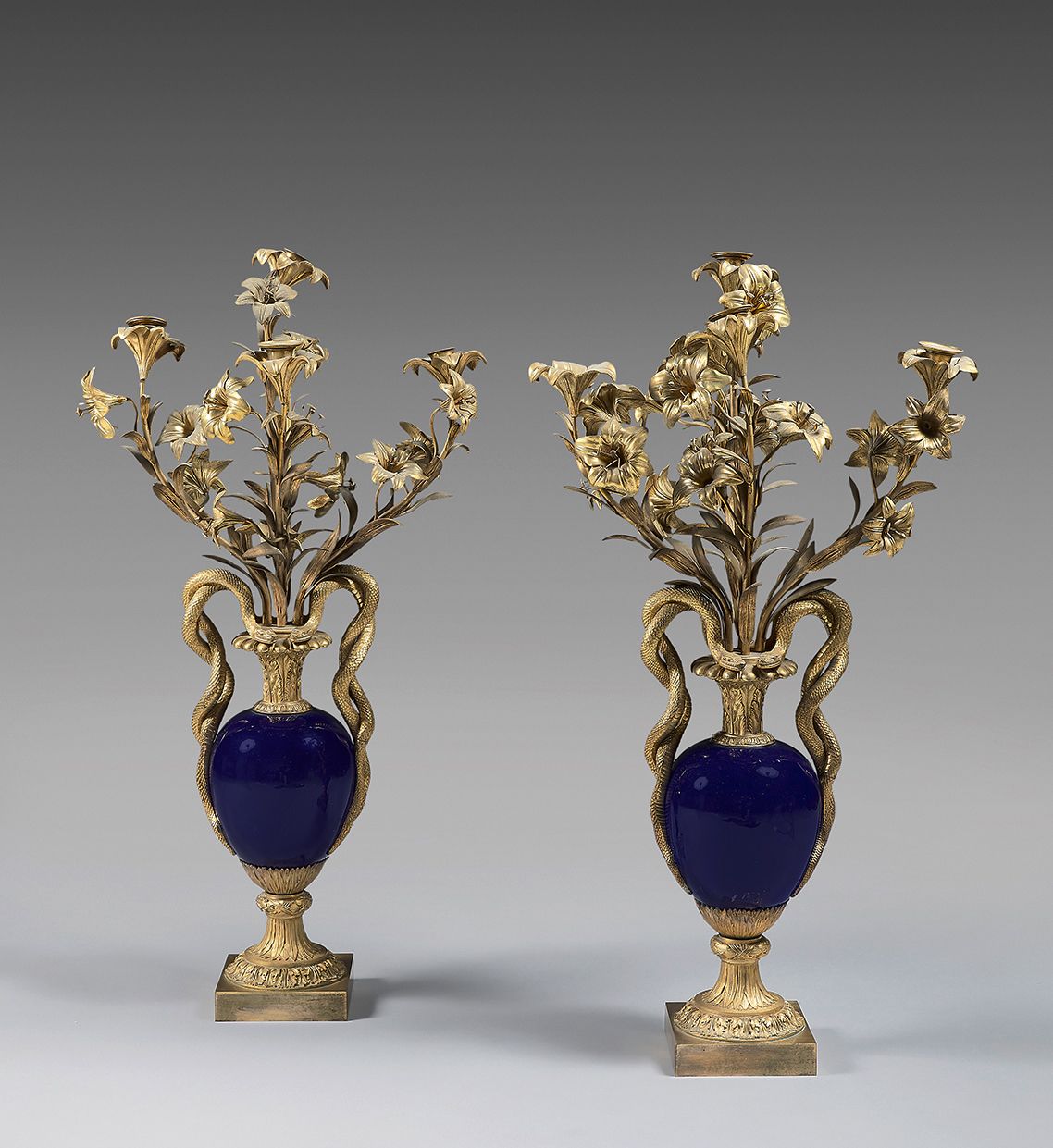 Null 一对五灯的瓷器和带花纹的兰花烛台，其形式为模拟花瓶，卵形的瓶身接受叶状百合花的灯束；分离的把手为交织的蛇形；水叶基座；四角形的底座。
19世纪末（分离&hellip;