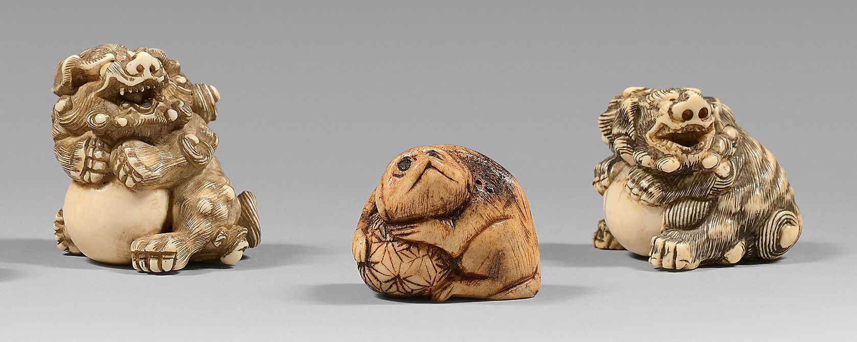 JAPON - Époque EDO (1603-1868) 三件网饰，两件为象牙材质，描绘坐着的拿着球的狮子，一件为鹿茸材质，坐着的狗，眼睛镶嵌着。
高：3.&hellip;