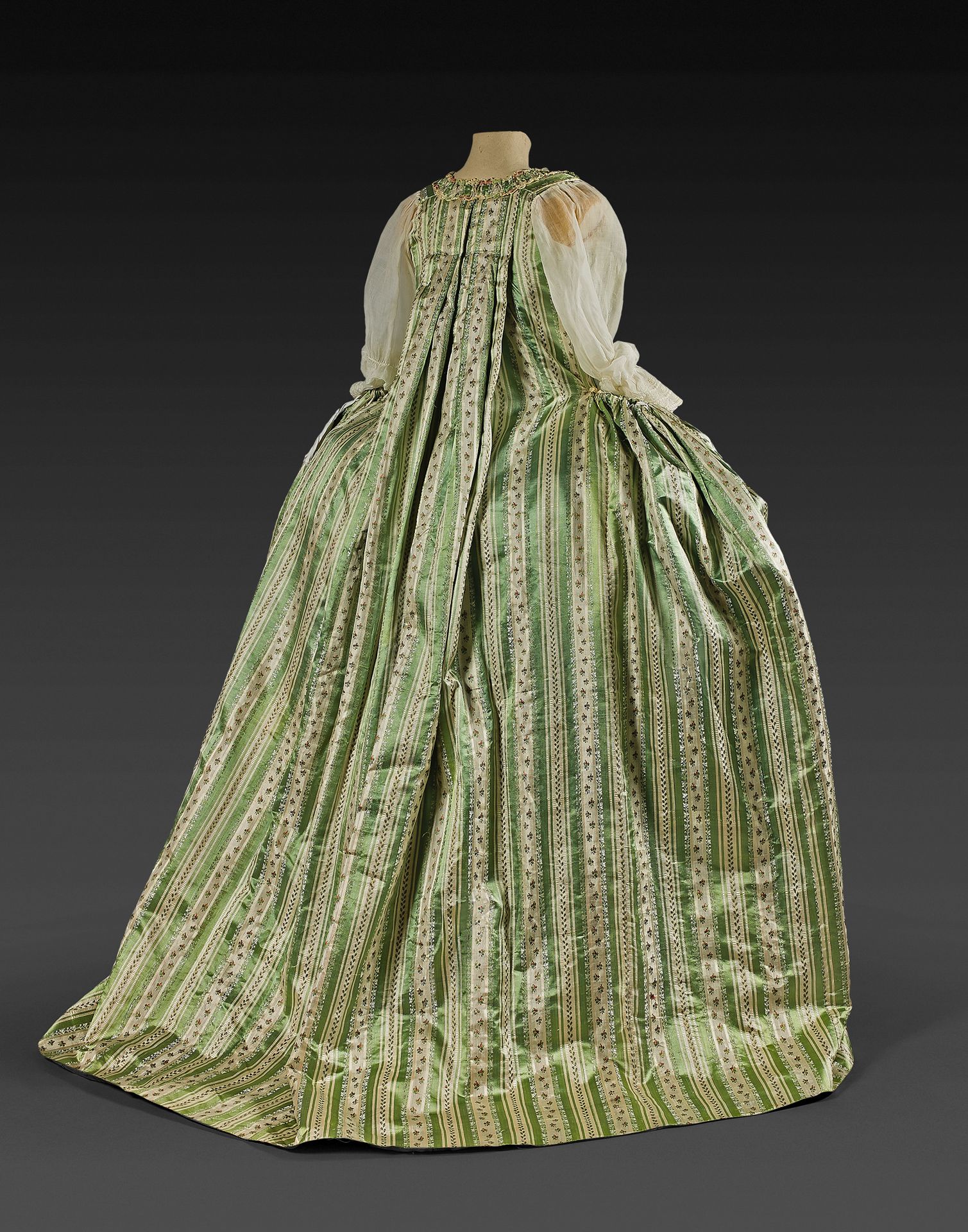 Null 法国礼服，路易十六时期，约1765-70。
薄荷绿色缎面背景的佩金，条纹上装饰着多色花，泡沫状的法尔巴拉被奶油色的丝质雪尼尔徽章衬托着。后面有华托褶的&hellip;